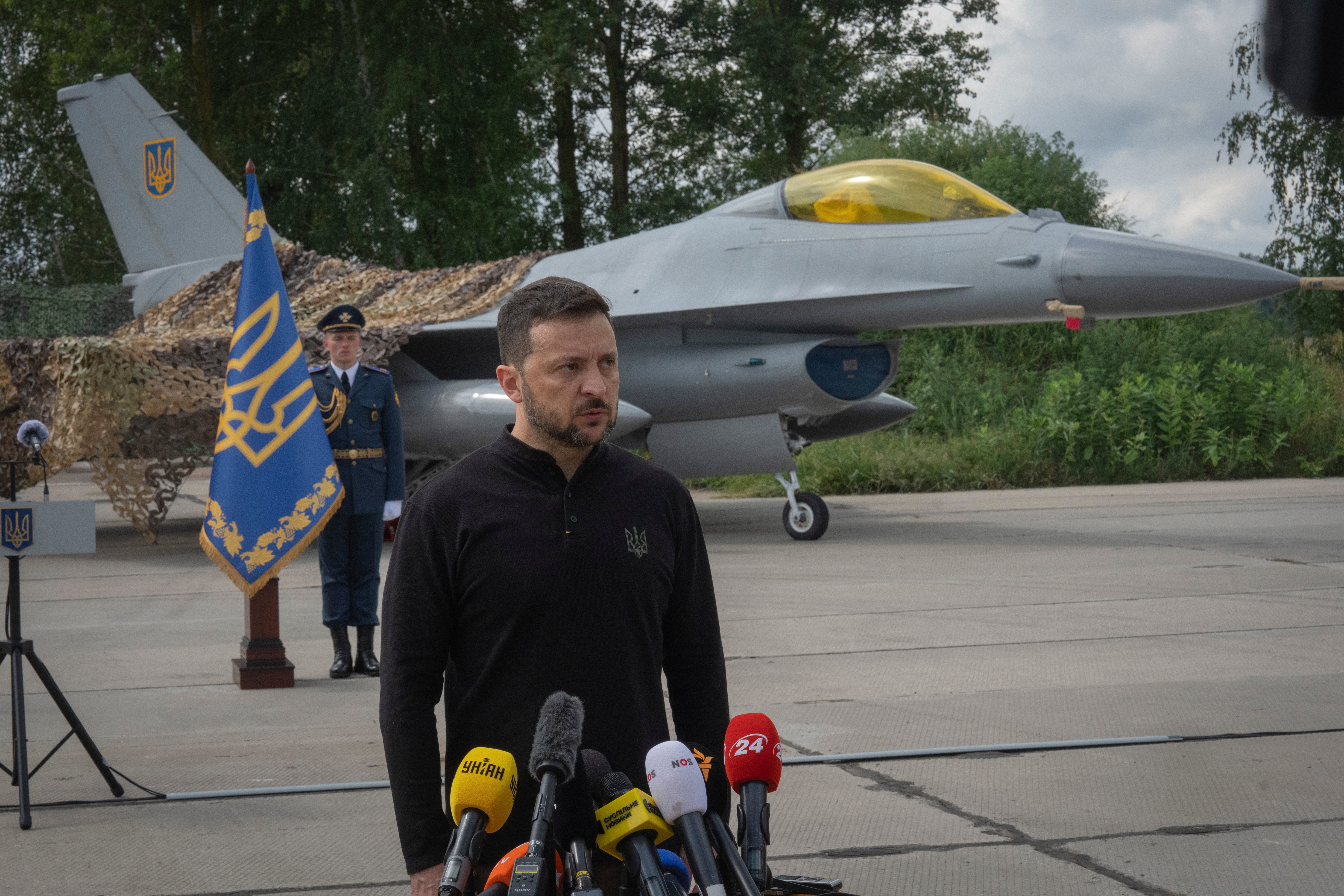 Ukraine’s president Volodymyr Zelensky answers media questions standing against the background of Ukraine’s Air Force’s F-16 fighter jets in an undisclosed location in Ukraine, Sunday, 4 August2024