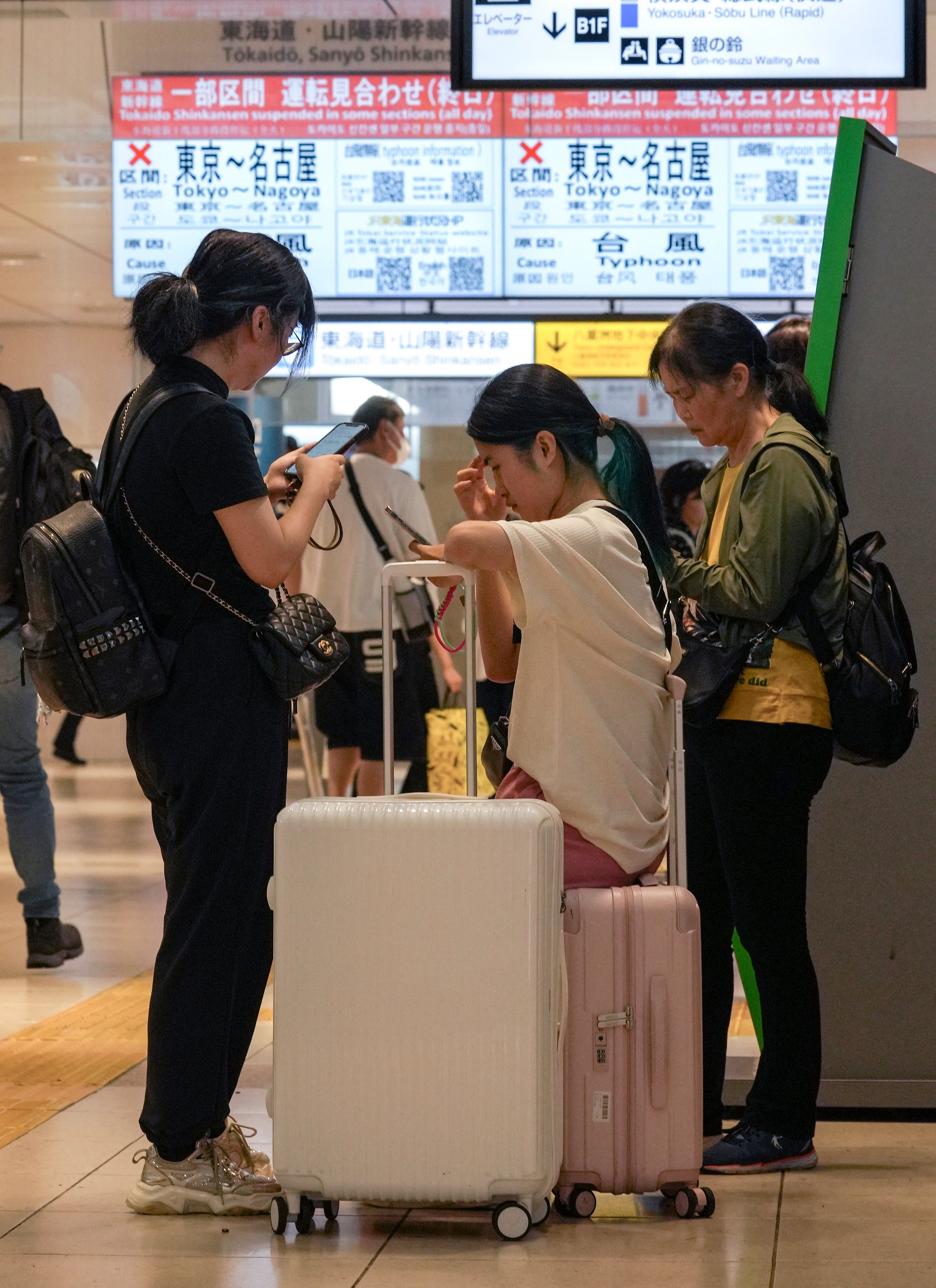 Passengers stand in front of displays showing information of the suspension of Tokaido Shinkansen bullet train service between Tokyo and Nagoya, at Tokyo railway station