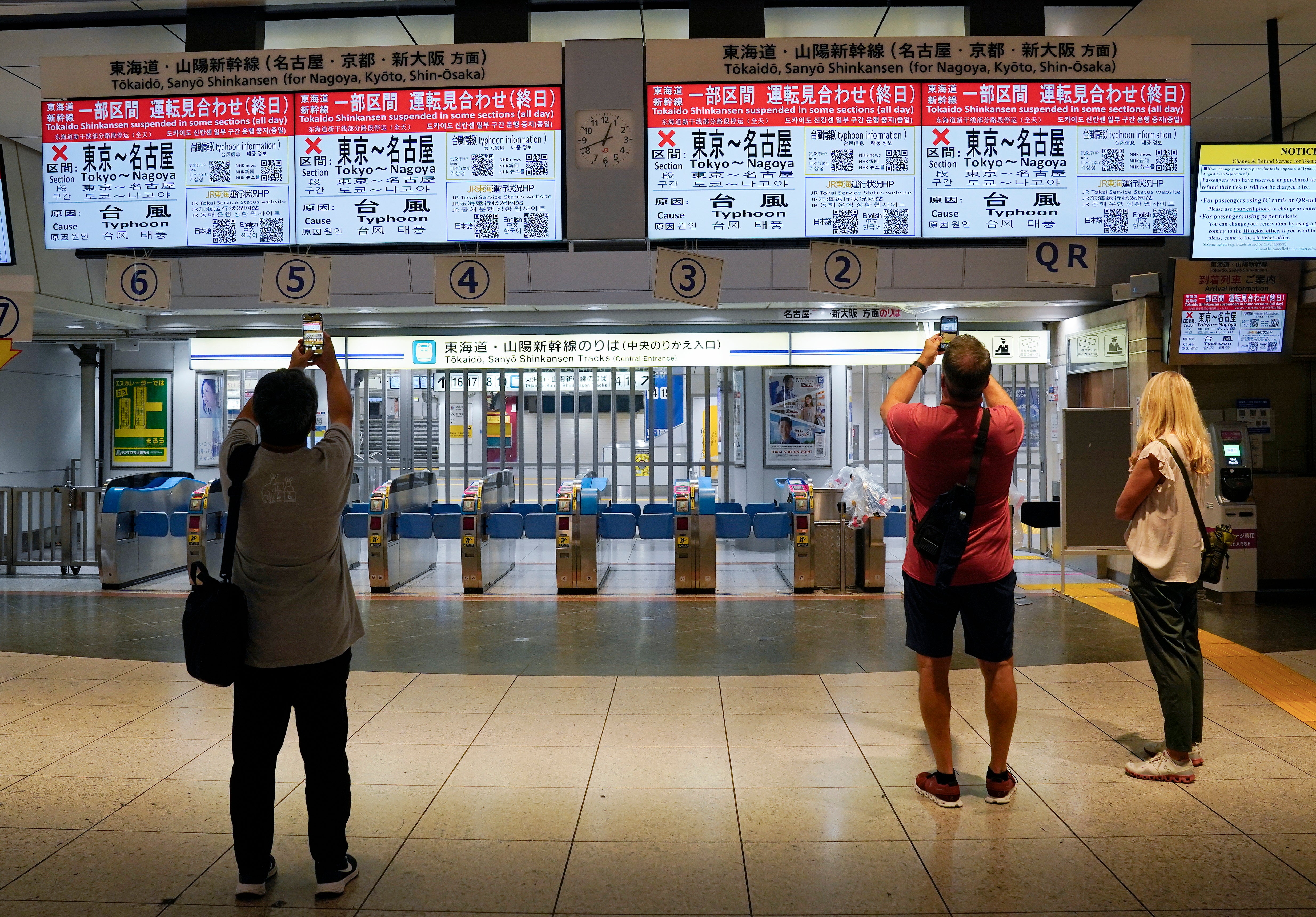 Passengers take pictures of displays showing information of the suspension of Tokaido Shinkansen bullet train service between Tokyo and Nagoya, at Tokyo railway station