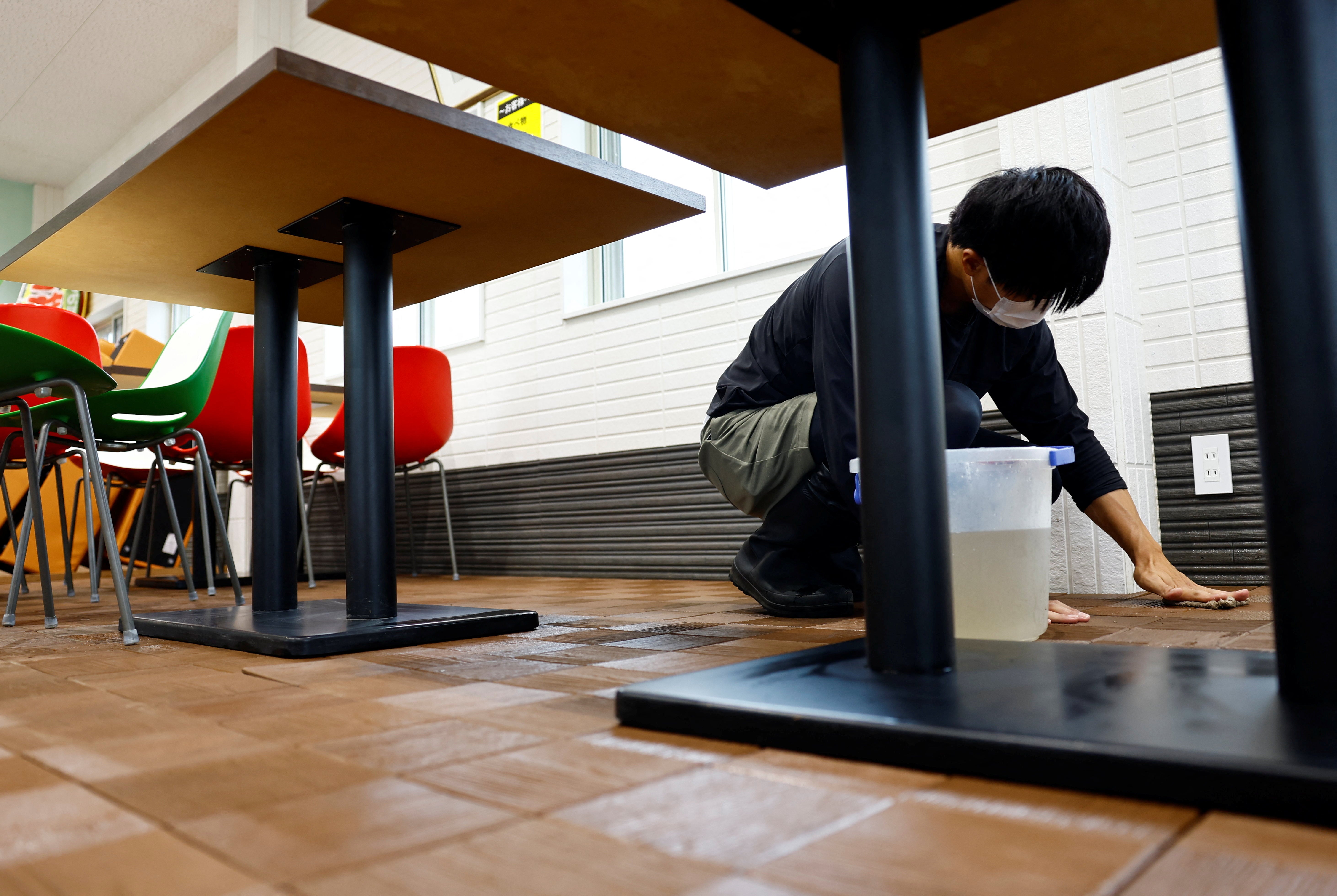 A man cleans a floor at a fish farm, after the facility was flooded during Typhoon Shanshan in Yufu