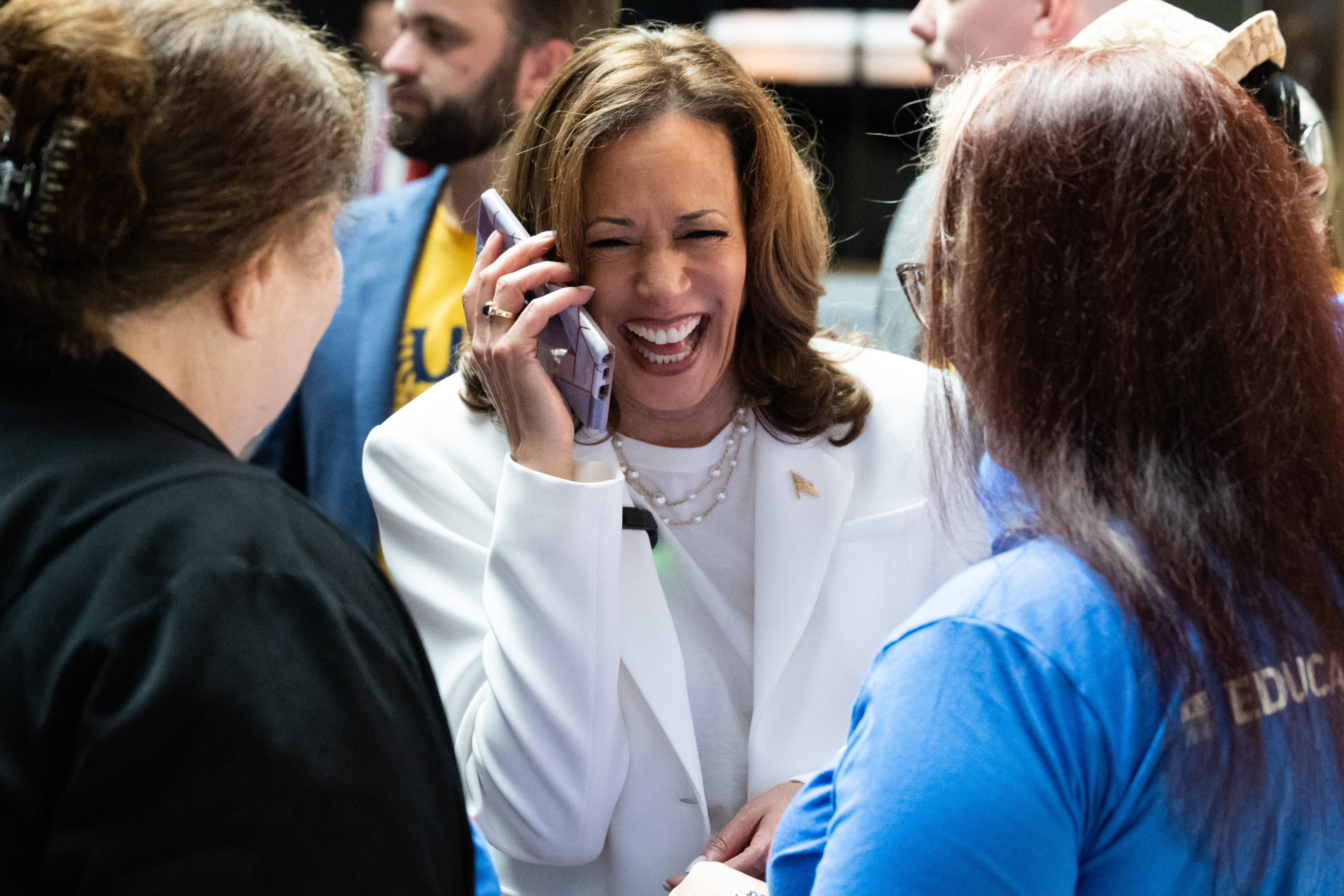 Democratic presidential candidate US Vice President Kamala Harris speaks to a supporter's daughter on a cellphone as she visits a volunteer appreciation event at The Grey restaurant in Savannah, Georgia, August 29, 2024, during the second day of a campaign bus tour.