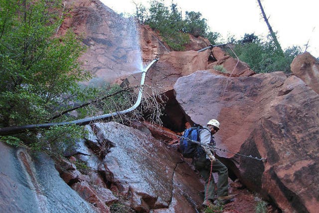 <p>Water spraying from a break in an exposed section of the Grand Canyon trans-canyon waterline as a worker attempts repairs</p>