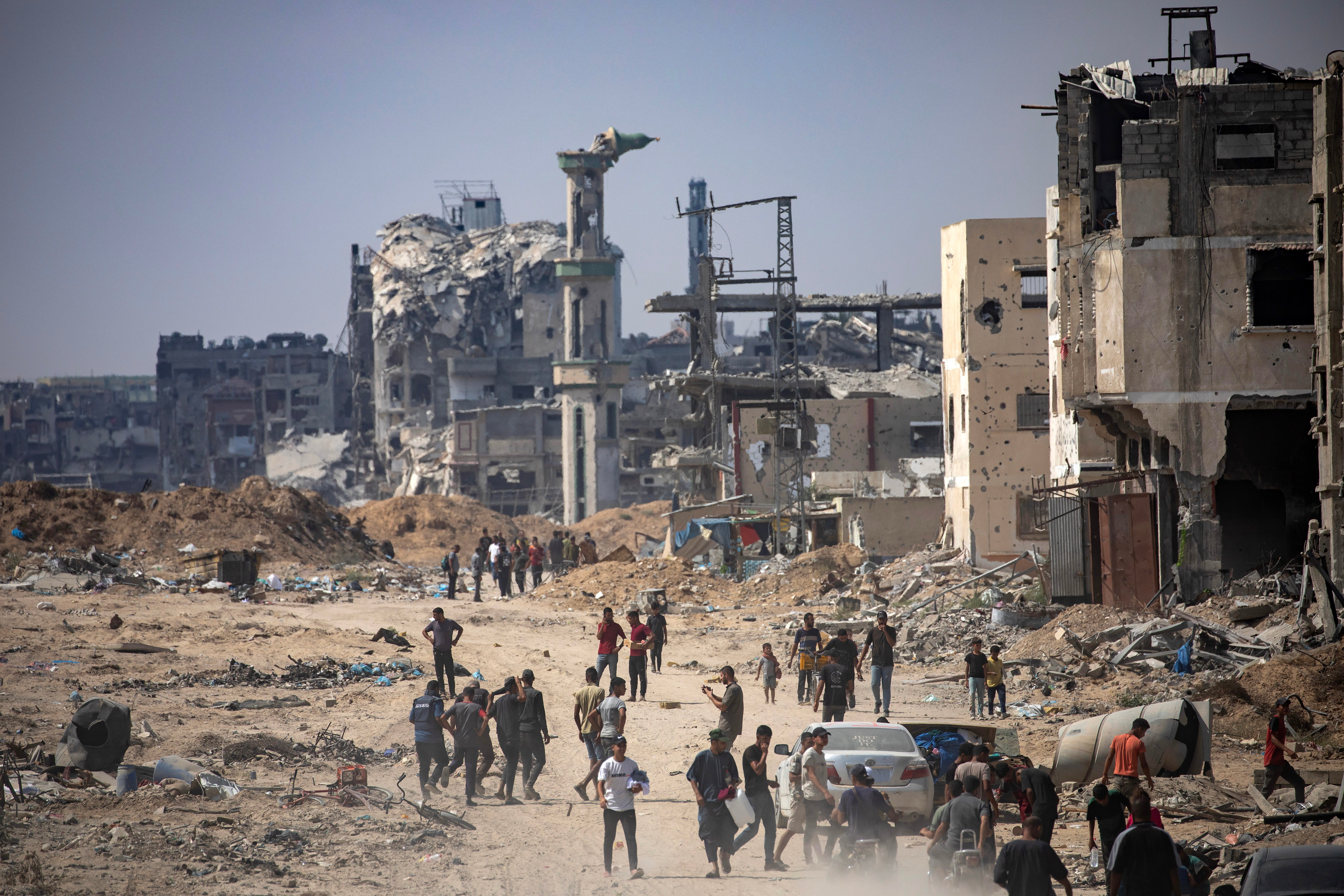 Internally displaced Palestinians move along a damaged street as they inspect the area after a ground military operation by Israeli forces, in Khan Younis camp, southern Gaza Strip, 30 August 2024