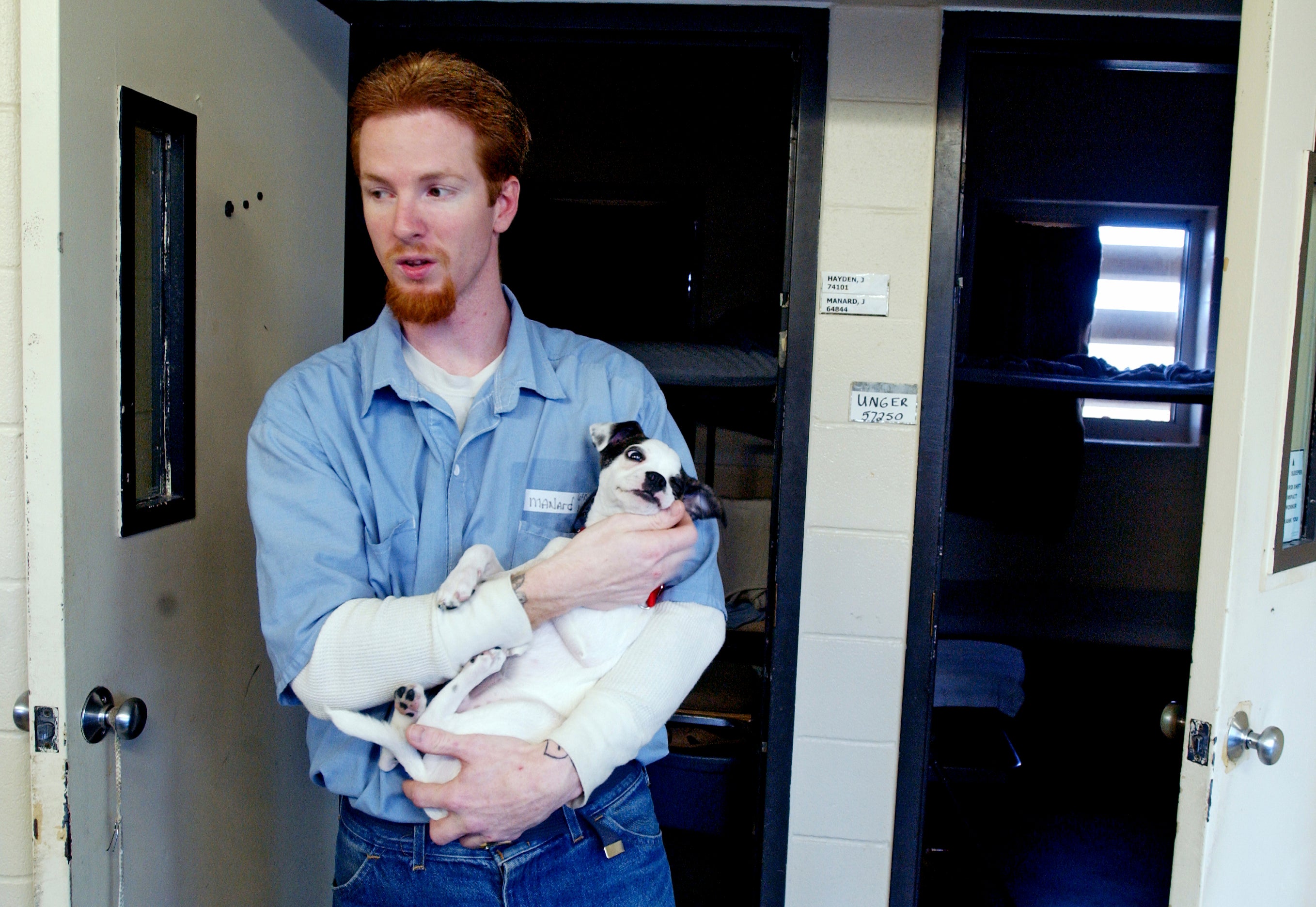 John Manard holding a puppy that was living in his cell block in January 2006