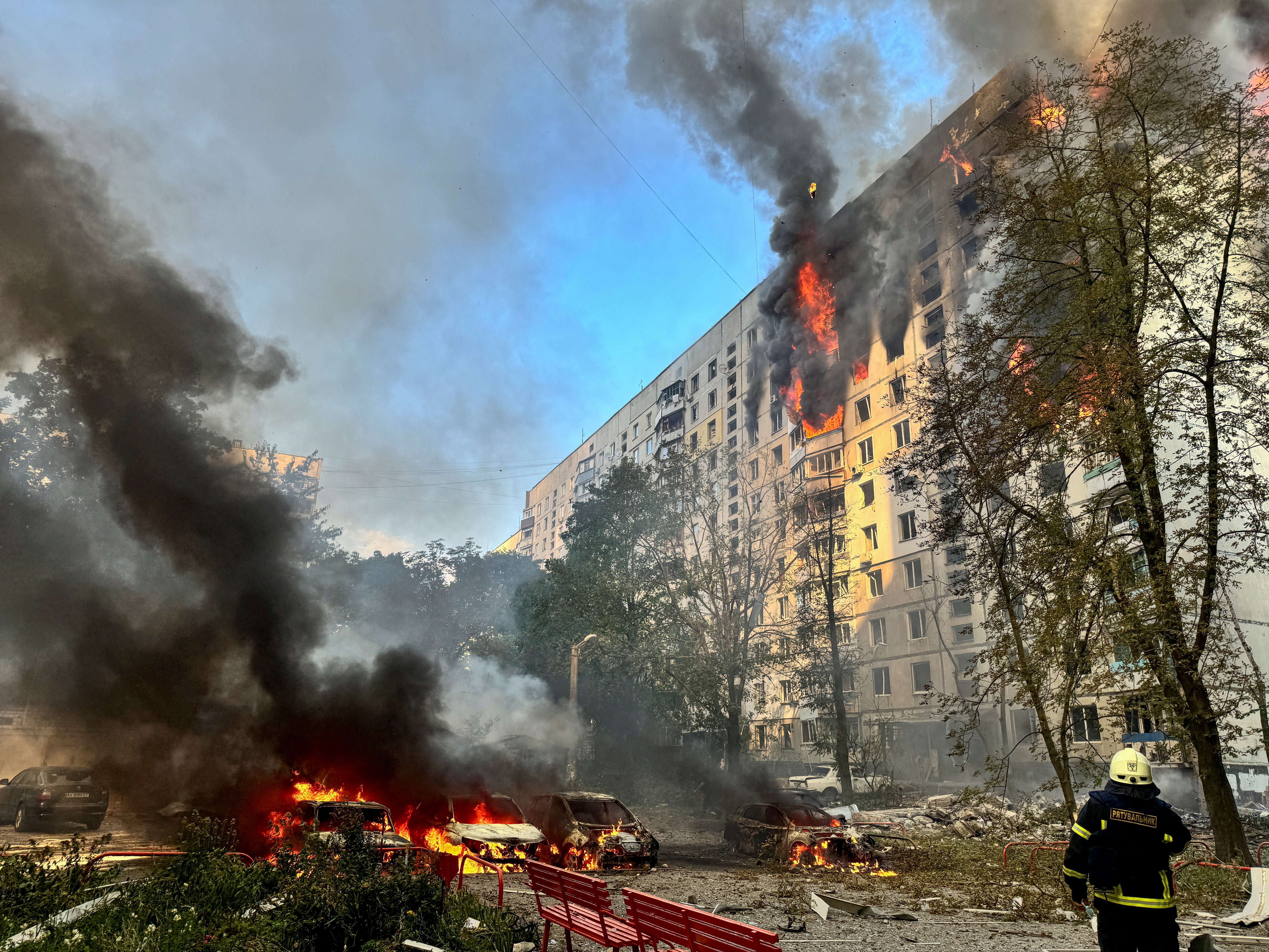 A firefighter looks at an apartment building and cars which burn after a Russian air strike in Kharkiv, northeast Ukraine