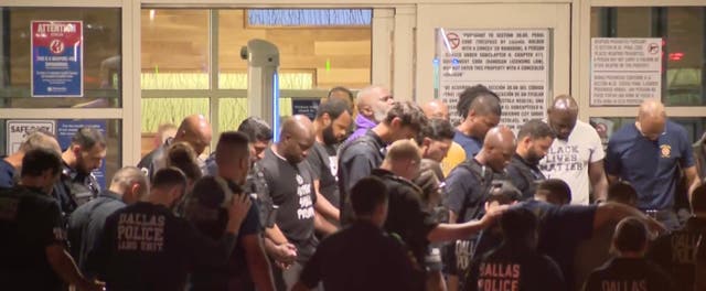 <p>Police officers outside the hospital where their colleagues are being treated. Flags at all Dallas facilities will be flown at half-staff out of respect for the officer who died after being shot on Thursday </p>