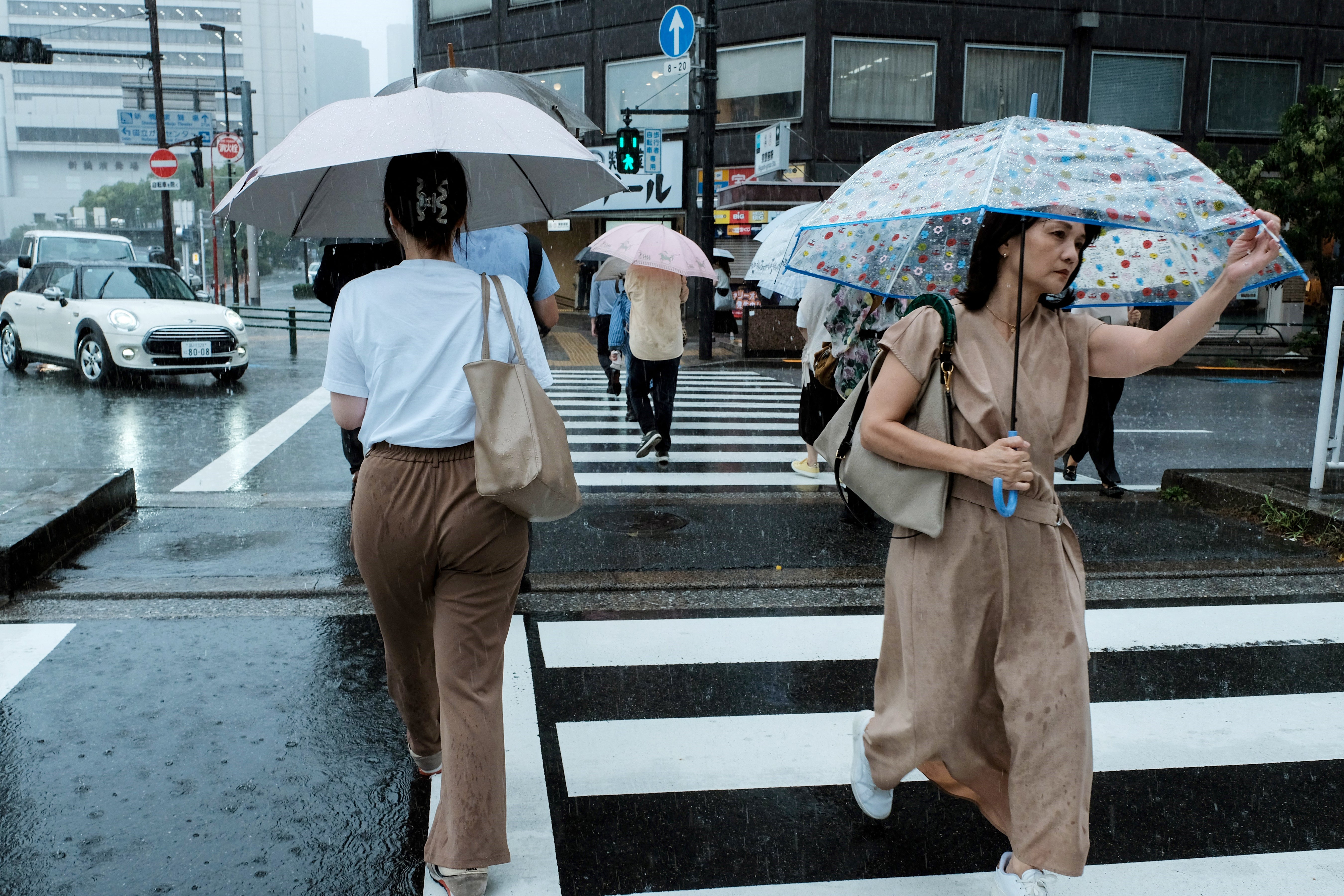 People walk across a street amid heavy rainfall in Tokyo