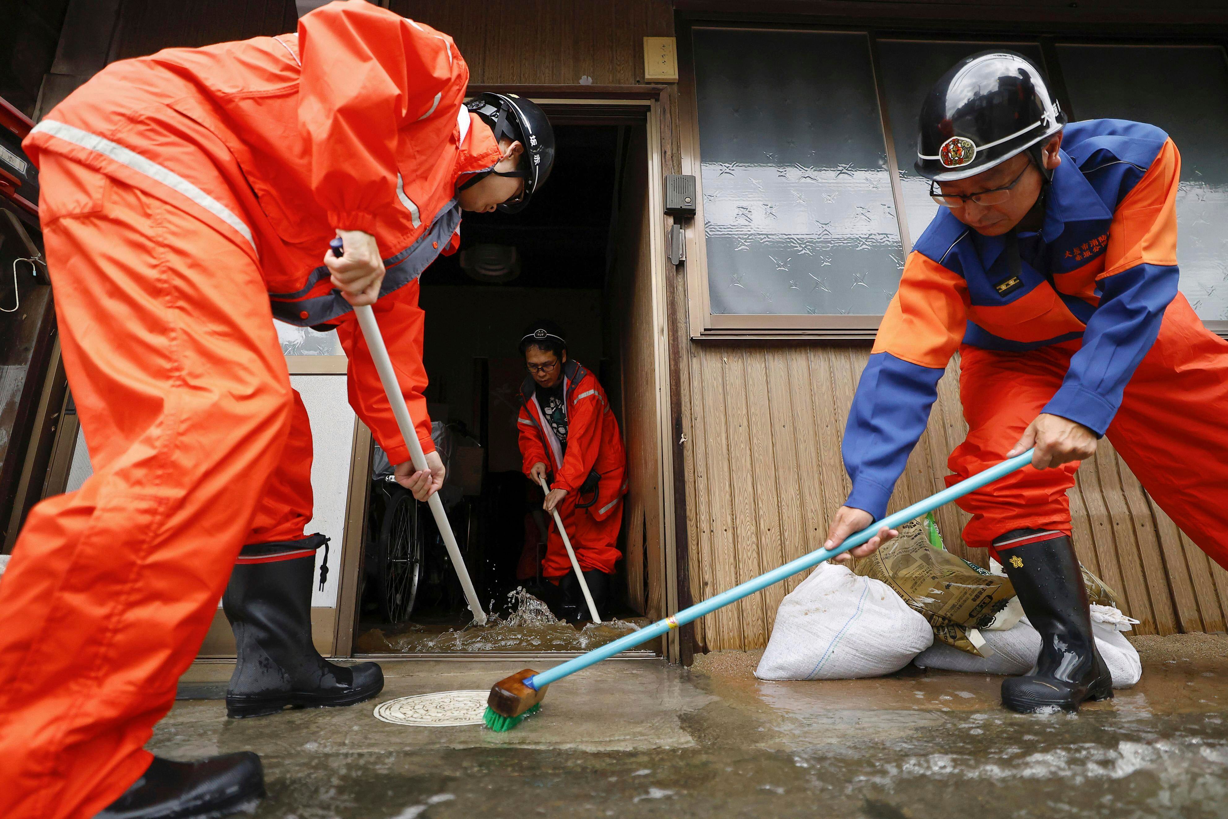 Firefighters help clean up a flooded house in Ogaki, central Japan, on Saturday