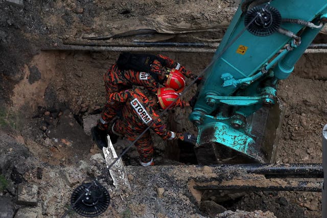 <p>Rescue workers inspect the site where a woman fell into a sinkhole in Kuala Lumpur, Malaysia </p>