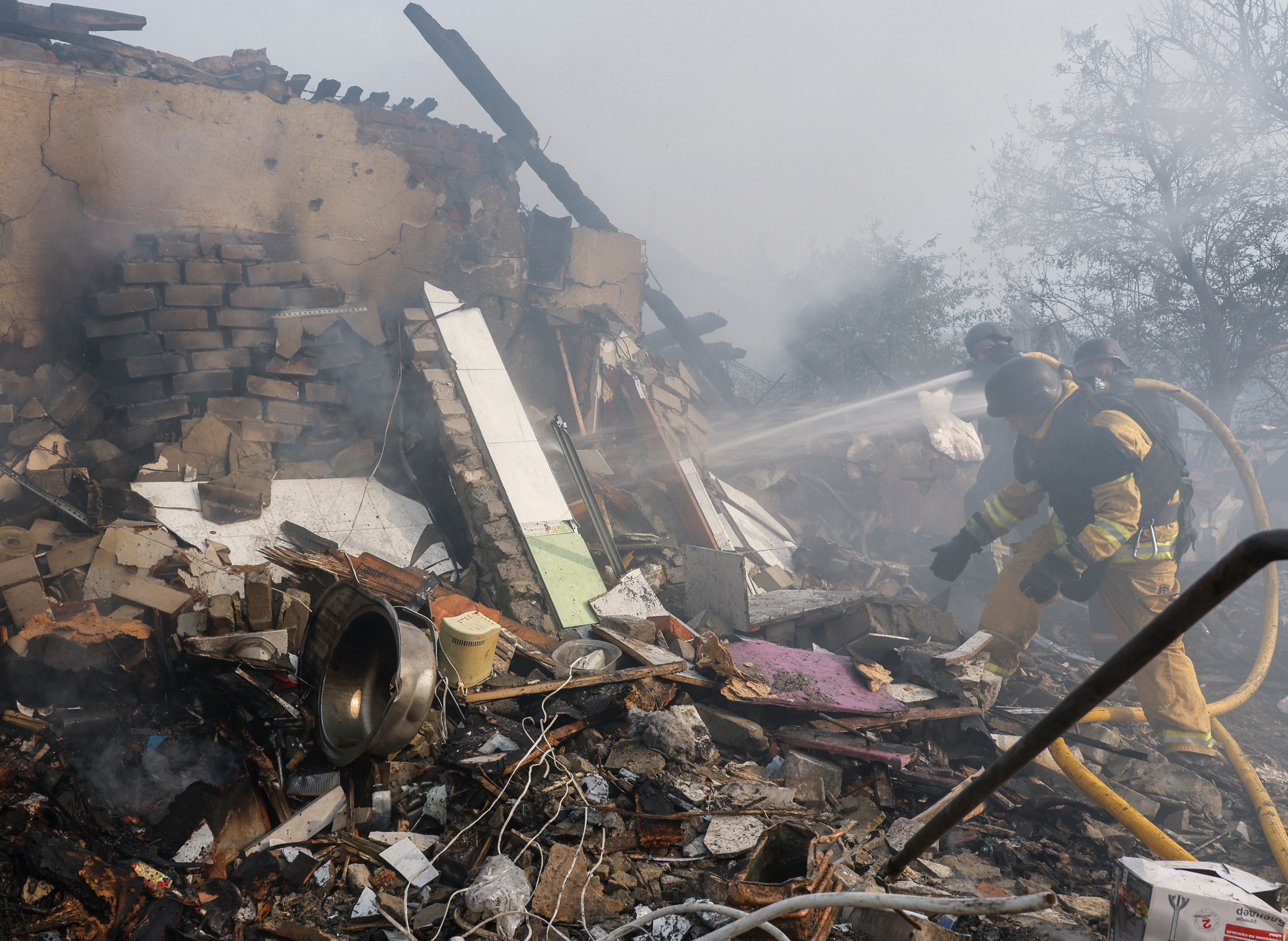 Ukrainian rescuers work at the site of a missile strike on a private building in Cherkaska Lozova