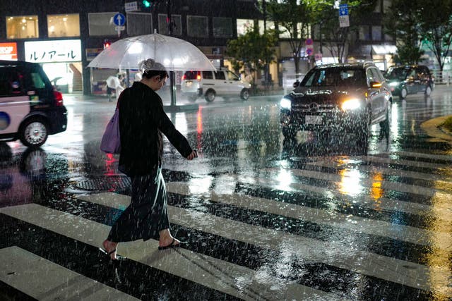 <p>A woman walks across a street amid heavy rainfall in Tokyo </p>