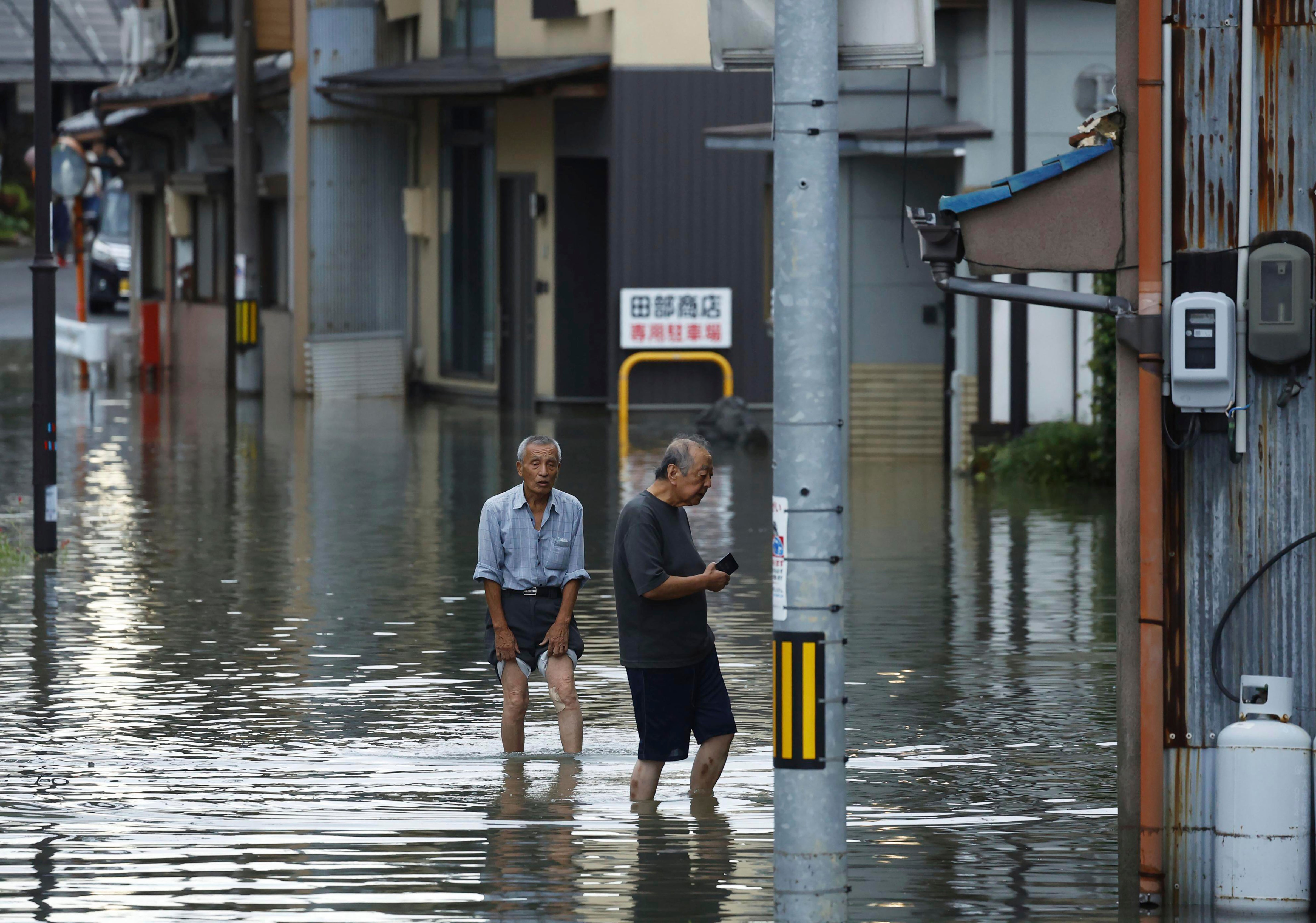 People wade through flooded streets as heavy rains flood the town of Ogaki in central Japan.