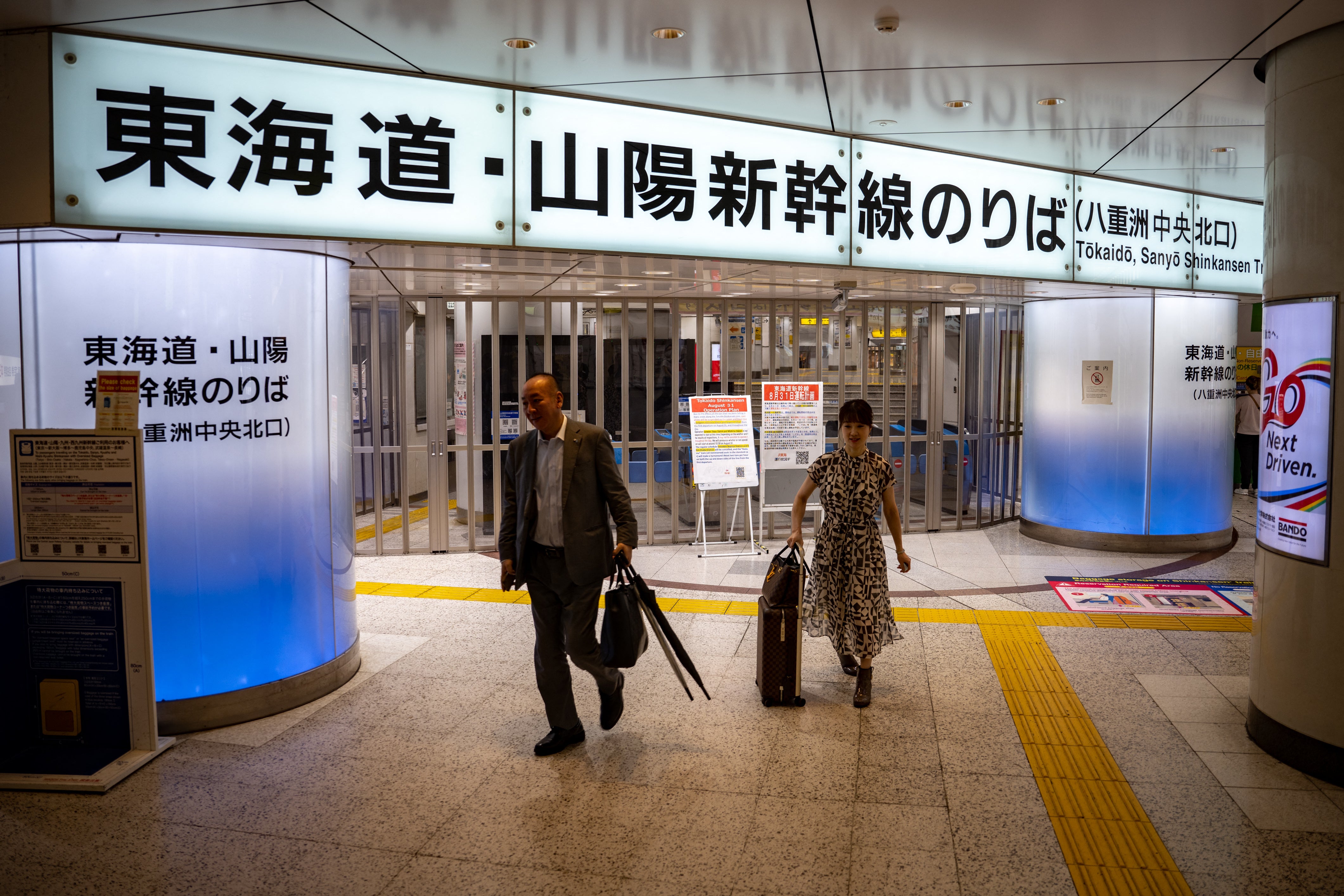 People walk past the closed ticket gates of the Tokaido Shinkansen Line at Tokyo Station as train service between Tokyo and Nagoya is suspended.