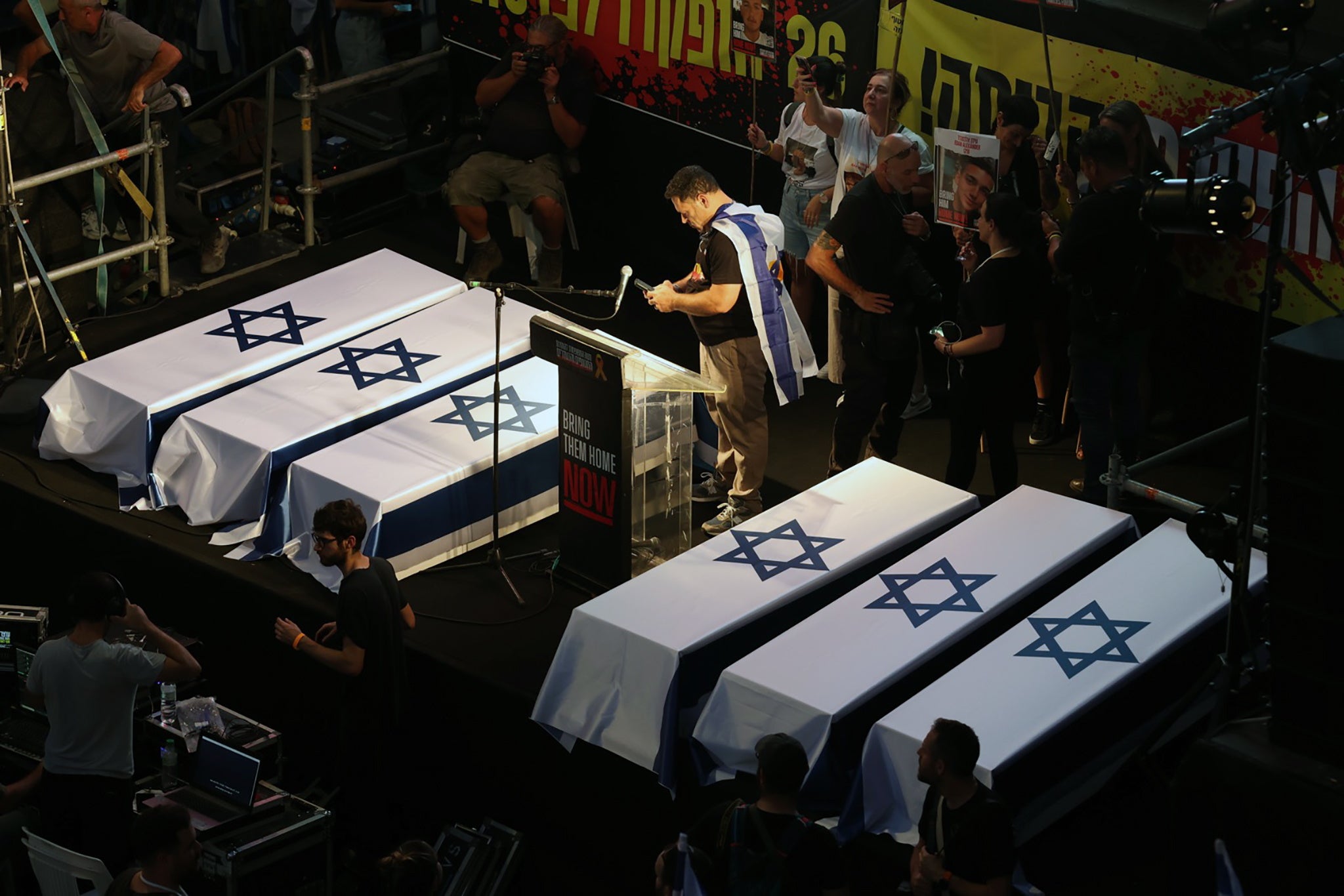 Protesters stand next to six mock coffins