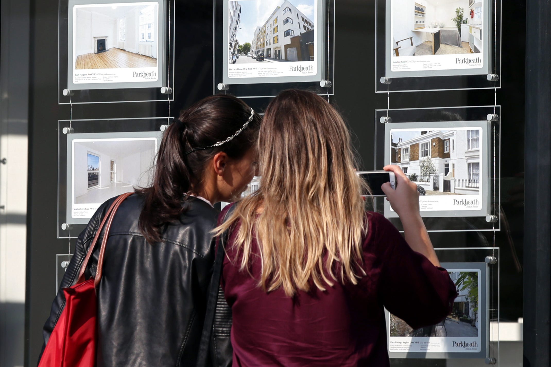 Two women looking at house price signs in an estate agent’s window