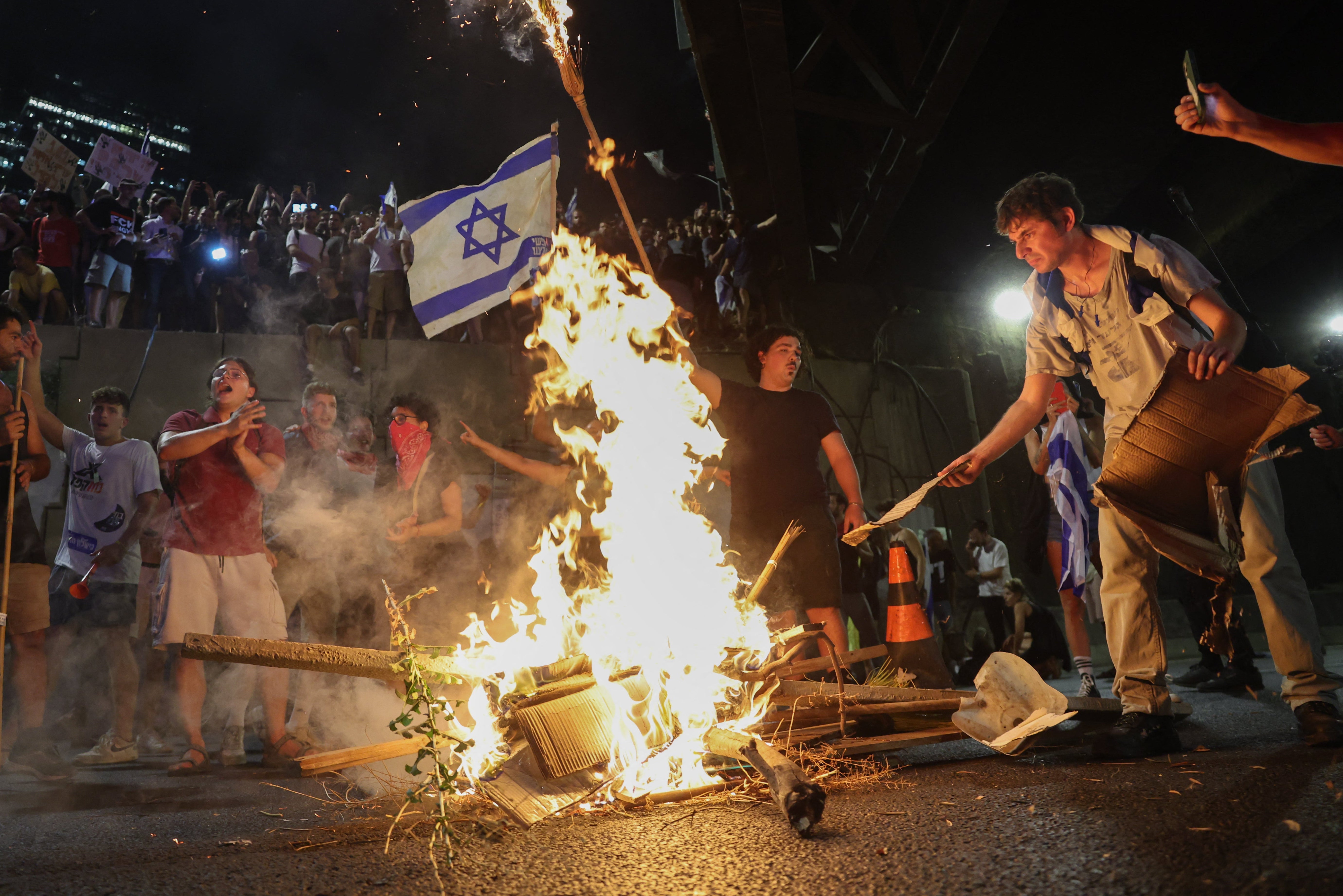 Protesters feed a fire during an anti-government rally calling for the release of Israeli hostages from Gaza