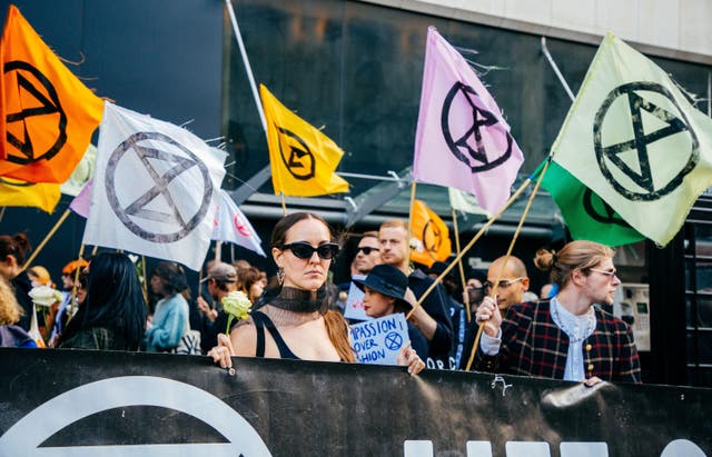 <p>File. Climate protestors hold flags outside the venue of the London Fashion Week</p>