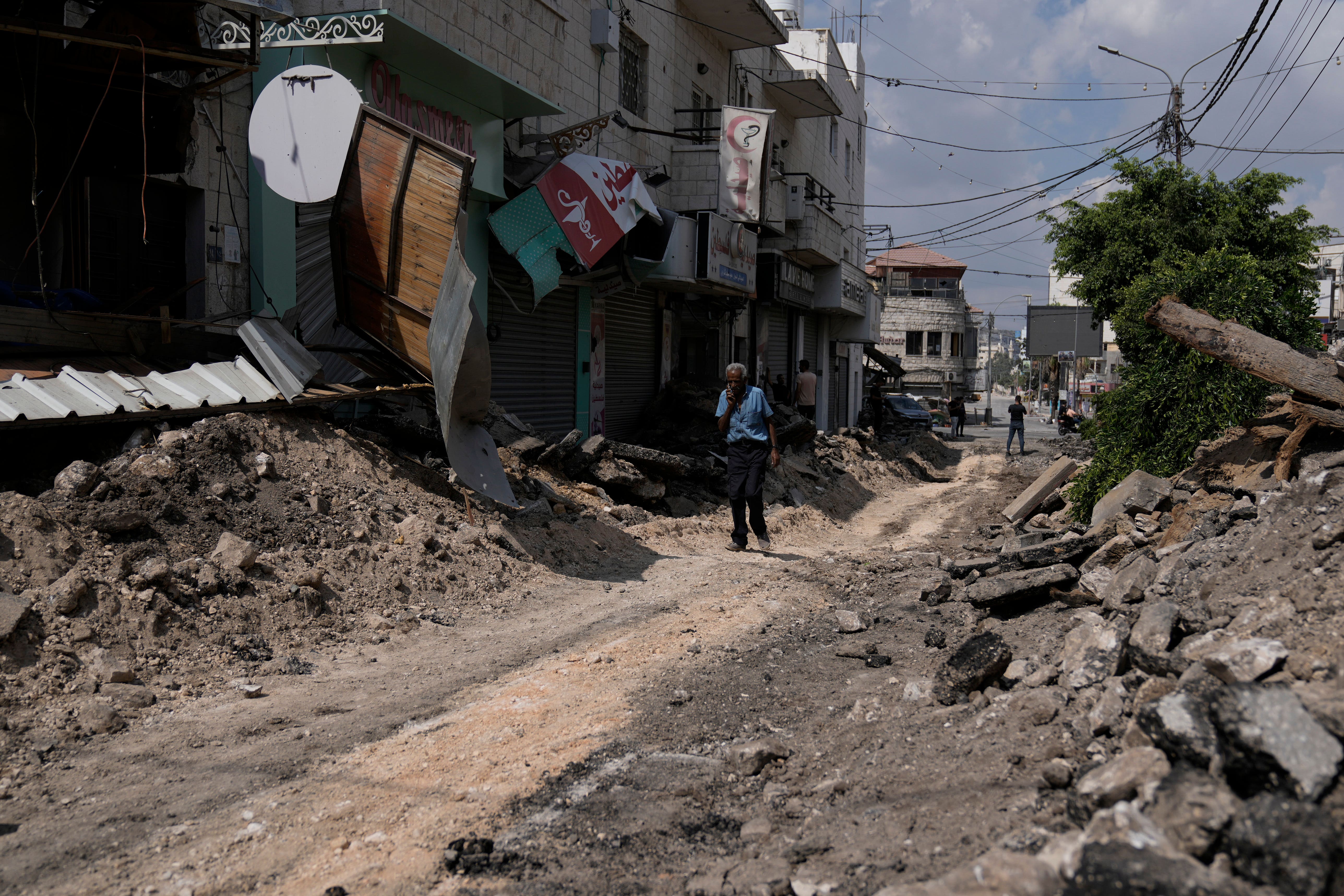 A Palestinian walks on a street damaged during a military operation in the West Bank city of Jenin (Majdi Mohammed/AP)