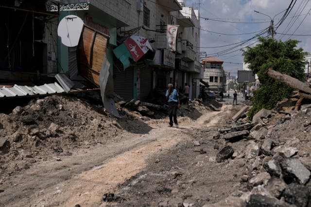 A Palestinian walks on a street damaged during a military operation in the West Bank city of Jenin (Majdi Mohammed/AP)