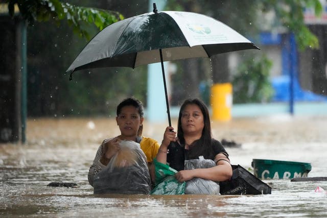 <p>Residents protect their belongings as they negotiate a flooded street caused by heavy rains from Tropical Storm Yagi, locally called Enteng, in Cainta, Rizal province, Philippines</p>