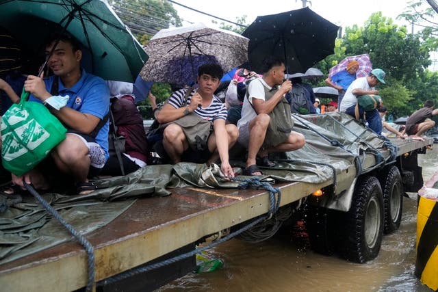 <p>Residents ride a truck as they negotiate a flooded street caused by heavy rains from Tropical Storm Yagi, locally called Enteng, in Cainta, Rizal province, Philippines</p>