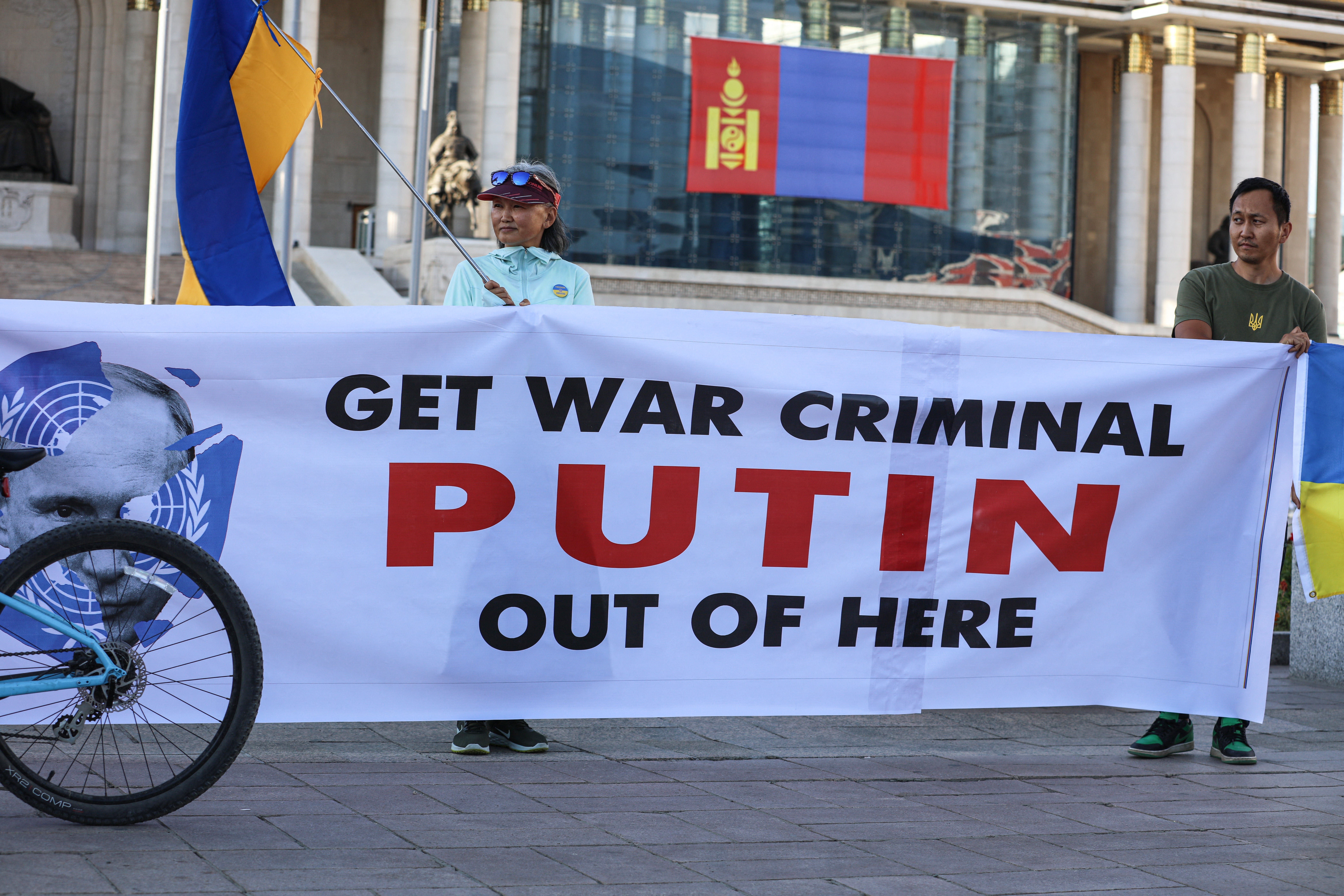 People holding Ukranian national flags and a banner take part in a protest ahead of a visit by Putin in Ulaanbaatar