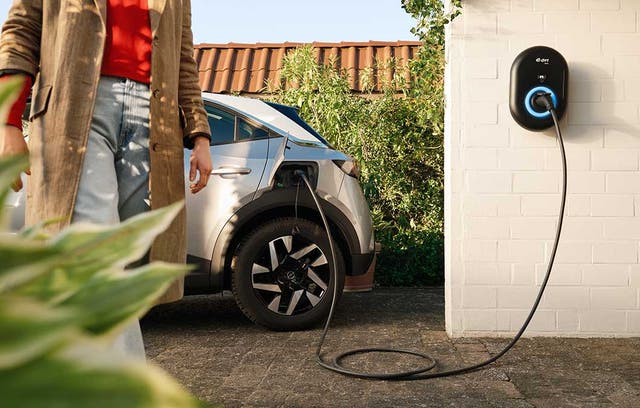 <p>An electric car plugged into a home charger </p>