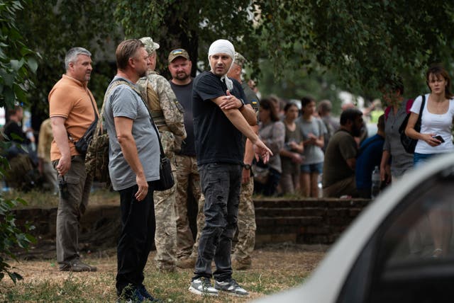 <p>People stand in the street near the Poltava Military Institute of Communications after a Russian missile attack on Tuesday </p>