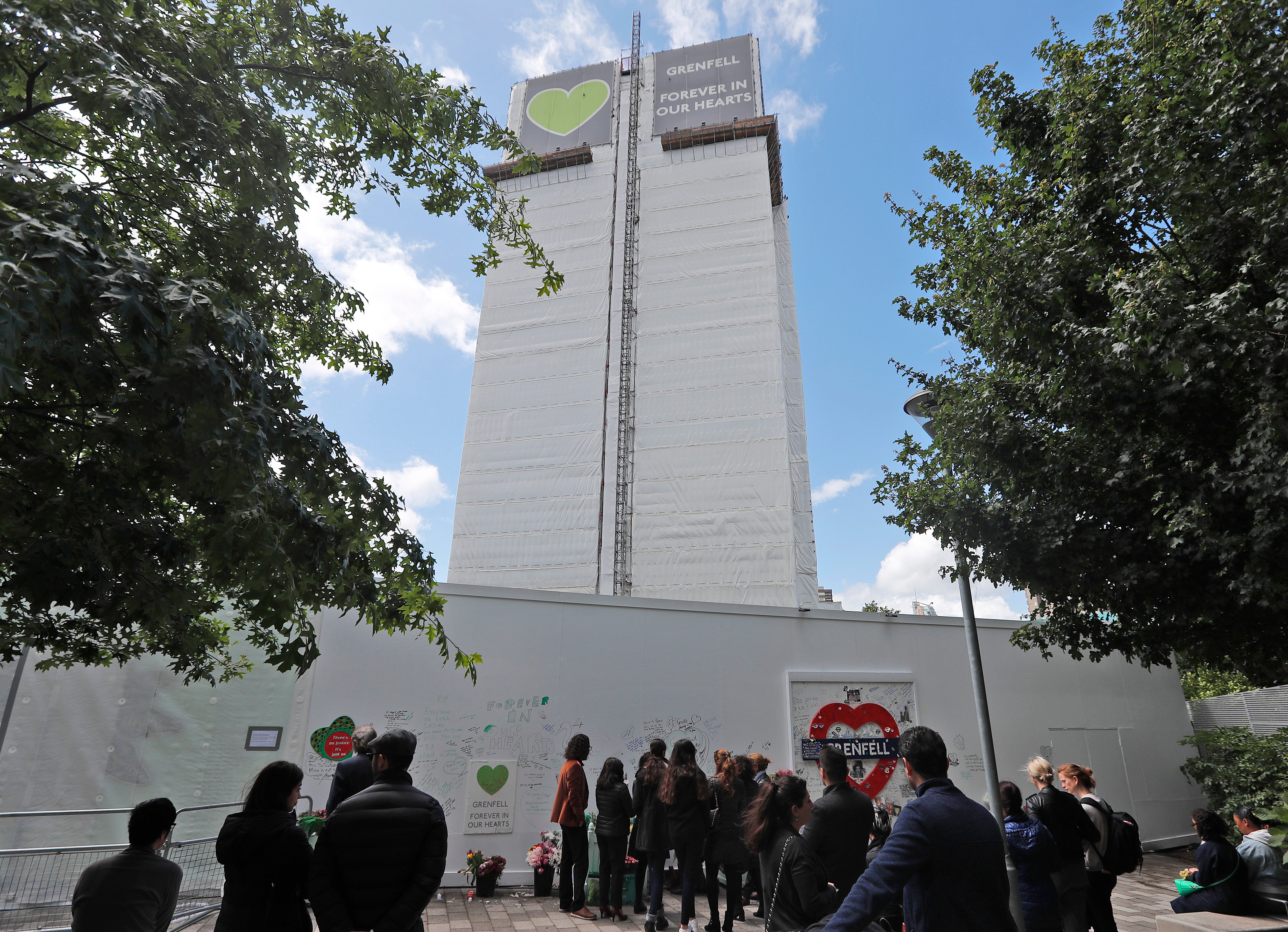 People pay their respects at the Grenfell tower to mark the two-year anniversary of the Grenfell Tower block fire, in London, Friday, June 14, 2019