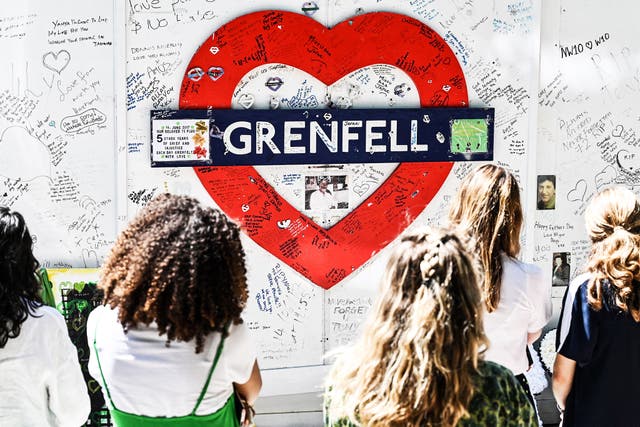 <p>People gather in front of the makeshift memorial created on the wall surrounding Grenfell tower in west London</p>