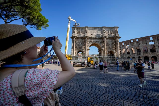 <p>A tourist takes photos of the 315 A.D Arch of Constantine, near the Colosseum, in Rome, Wednesday, September 4</p>