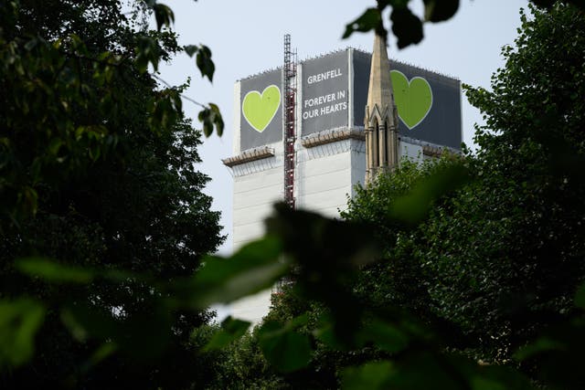 <p>The shrouded structure of Grenfell Tower is seen among the trees </p>