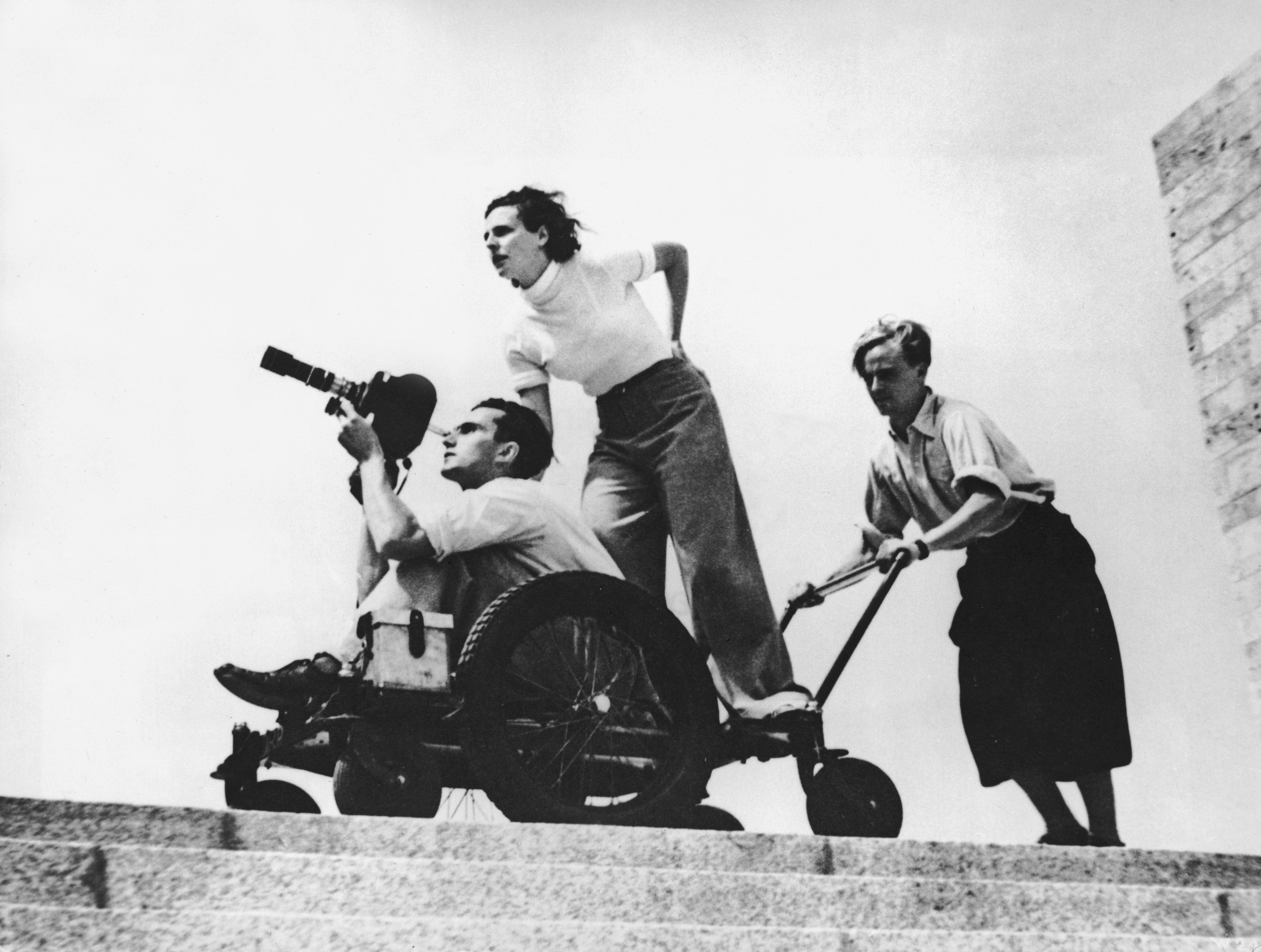 Riefenstahl and cameraman Walter Frentz being wheeled along by an assistant at the 1936 Berlin Olympics