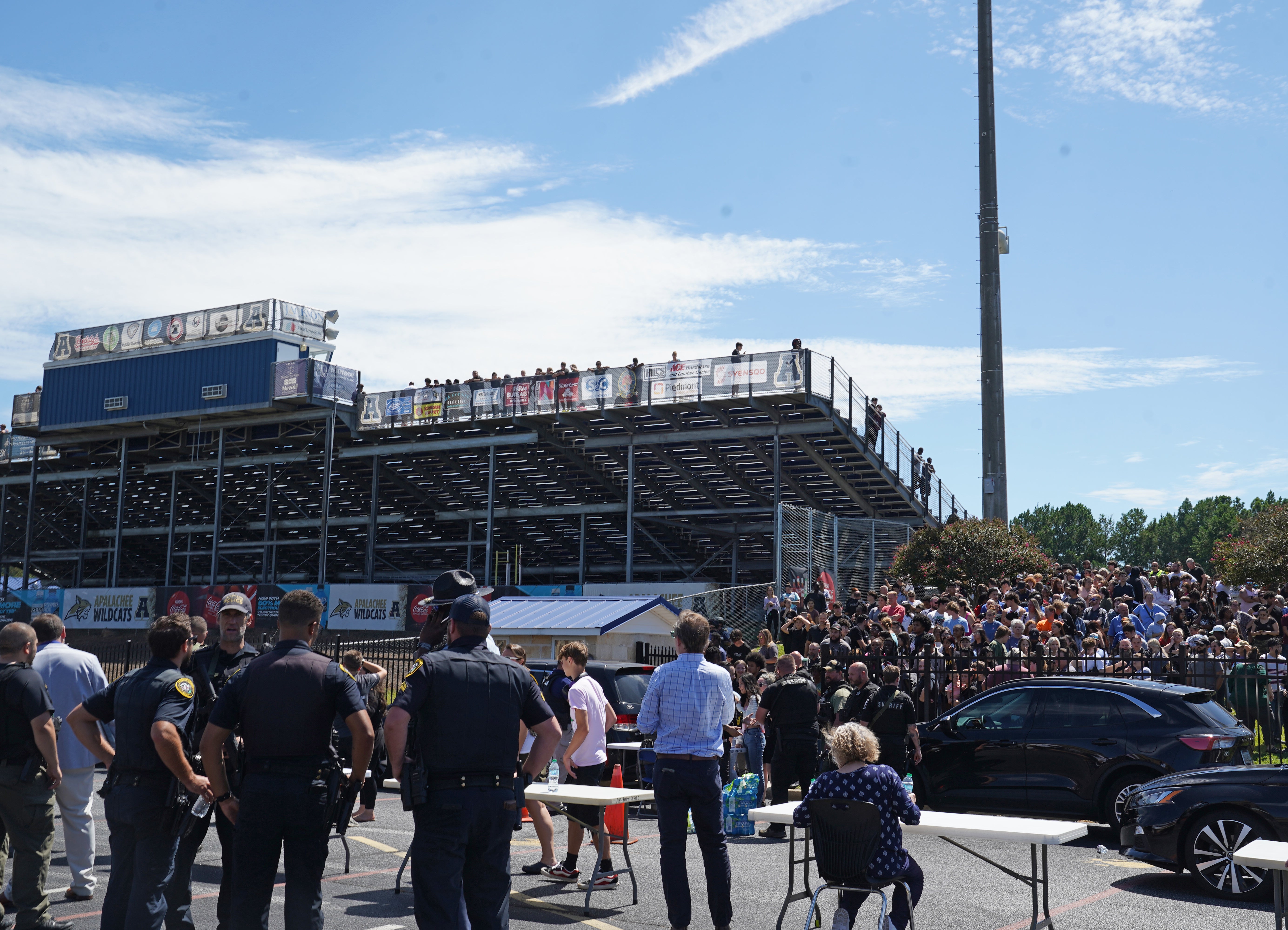 Students, law enforcement and parents gather at a nearby stadium after a mass shooting at Apalachee High School