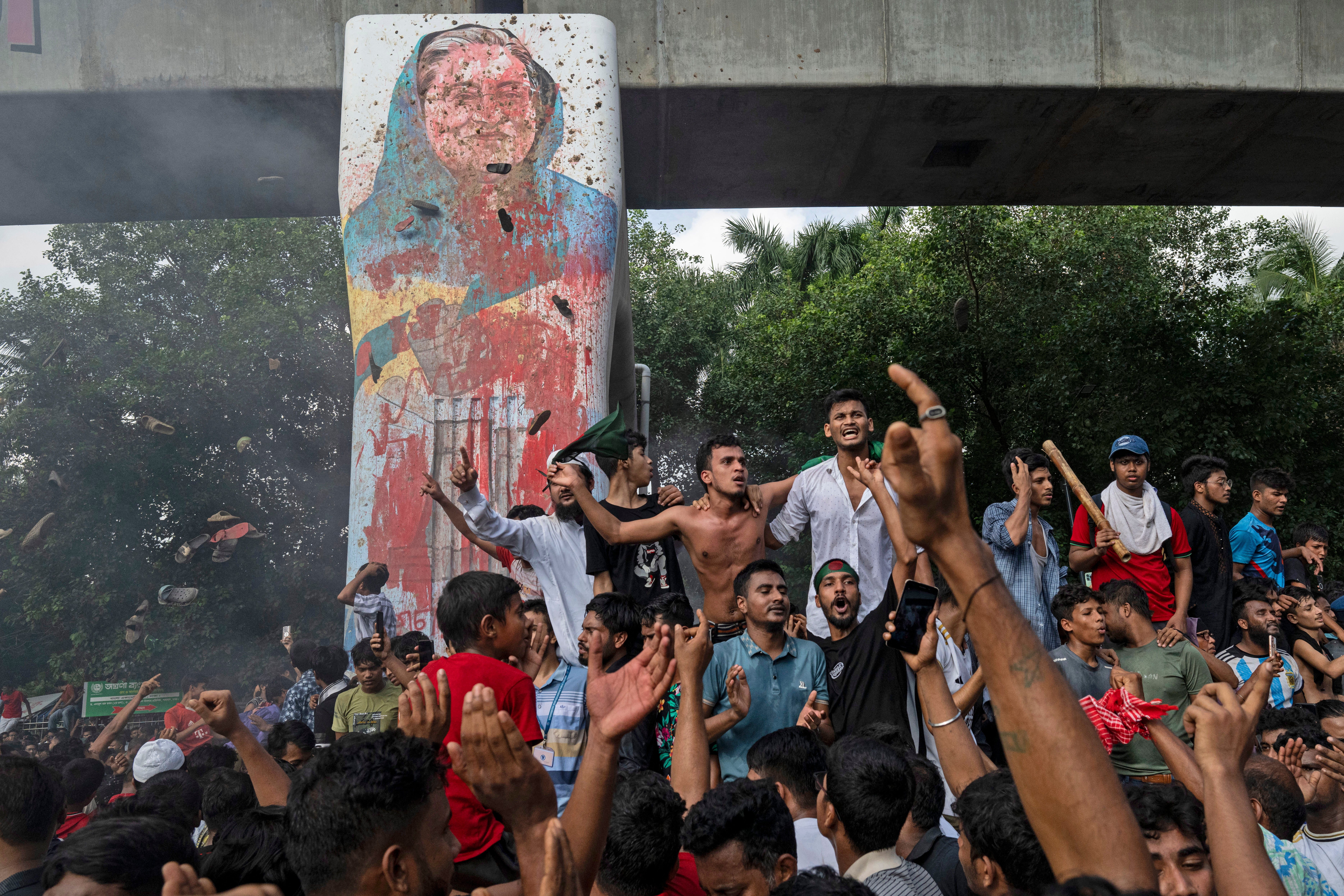 File. Protesters celebrate beside a defaced portrait of Sheikh Hasina after news of her resignation in Dhaka on 5 August 2024