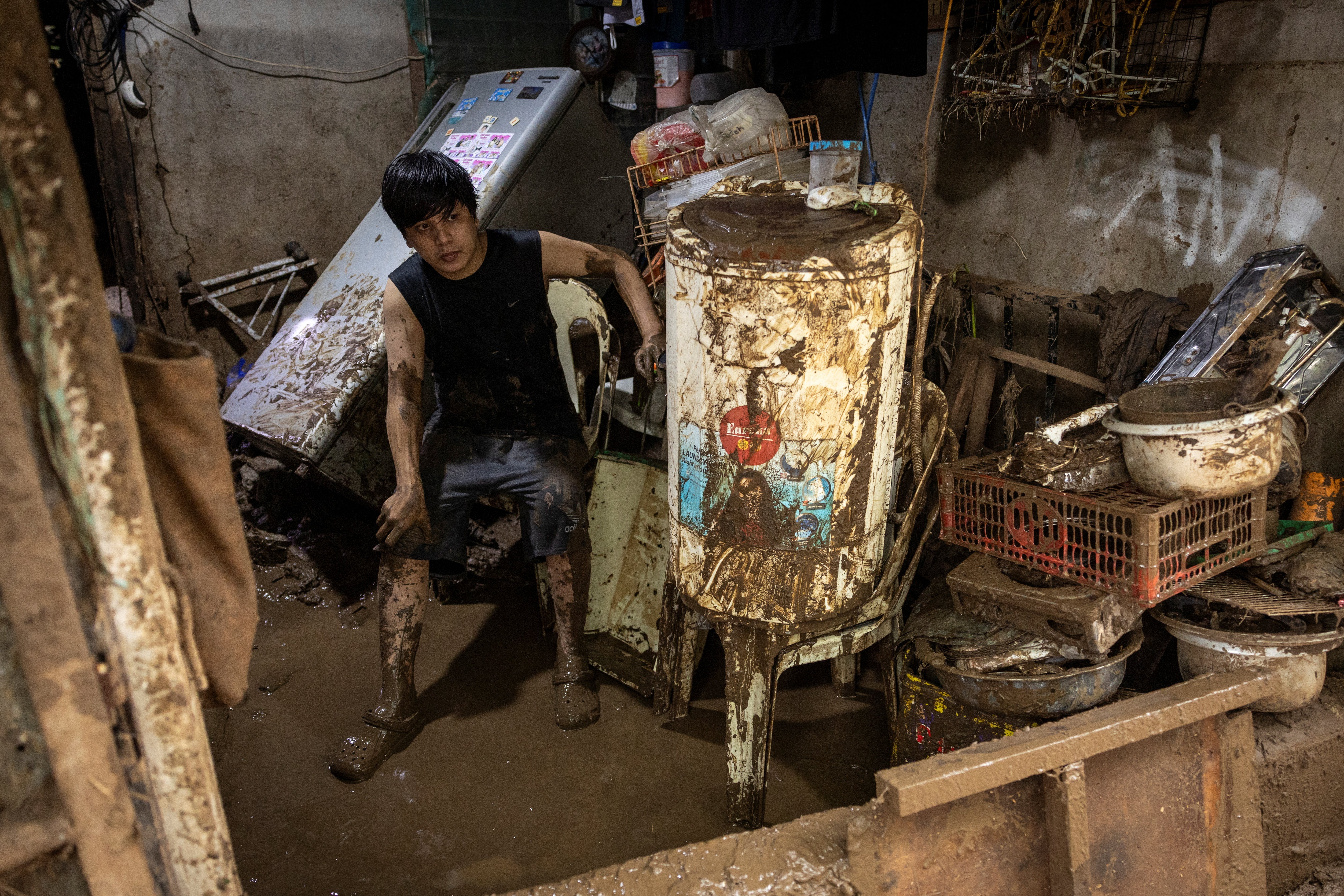 Jefernell Cervantes, 28, takes a break from his job of clearing mud after his home was flooded by Tropical Storm Yagi (known locally as Enteng) in Pililla, Rizal, Philippines.