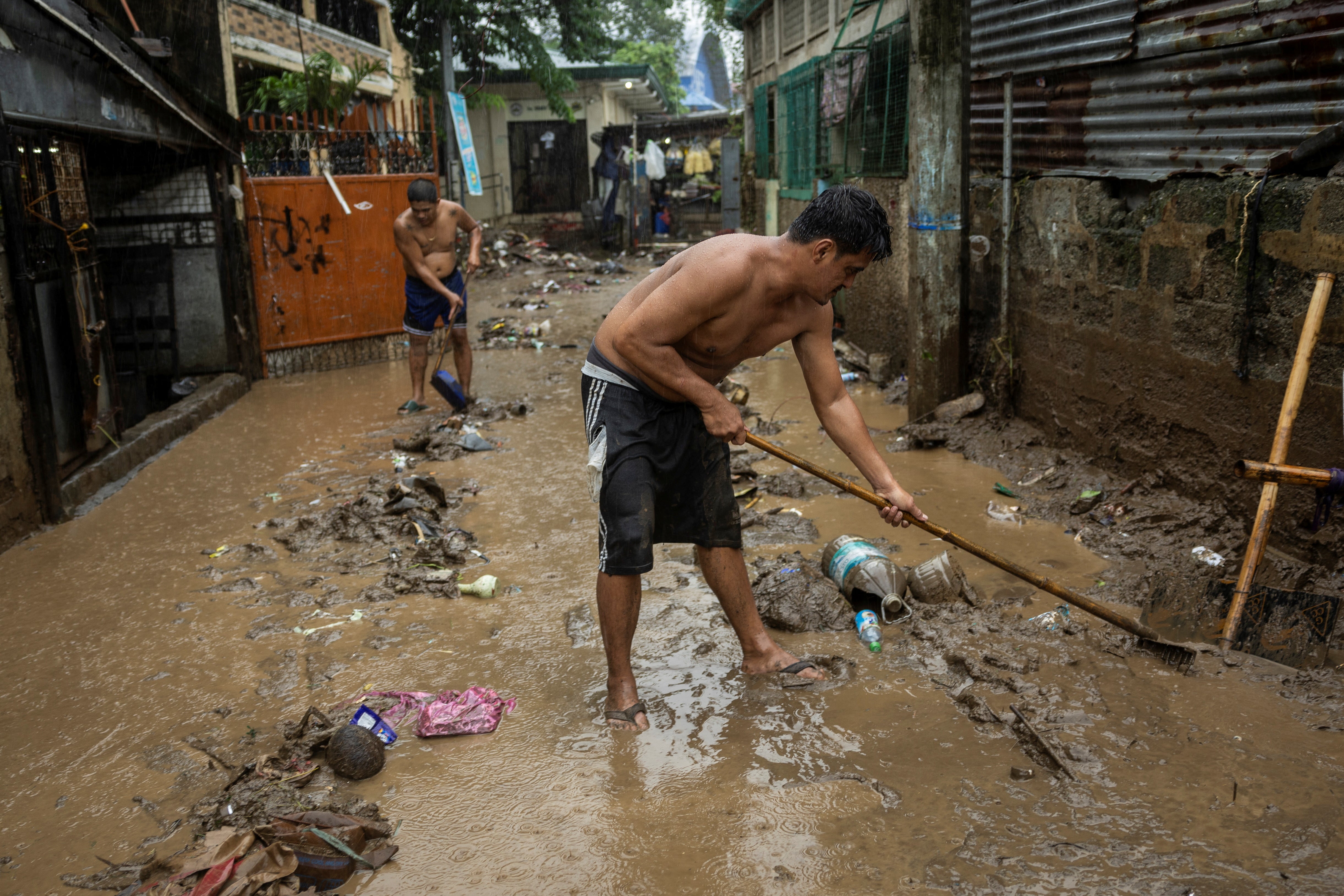 Residents sweep mud from a street in the aftermath of Tropical Storm Yagi (known locally as Enteng) in Pililla, Rizal province, Philippines.