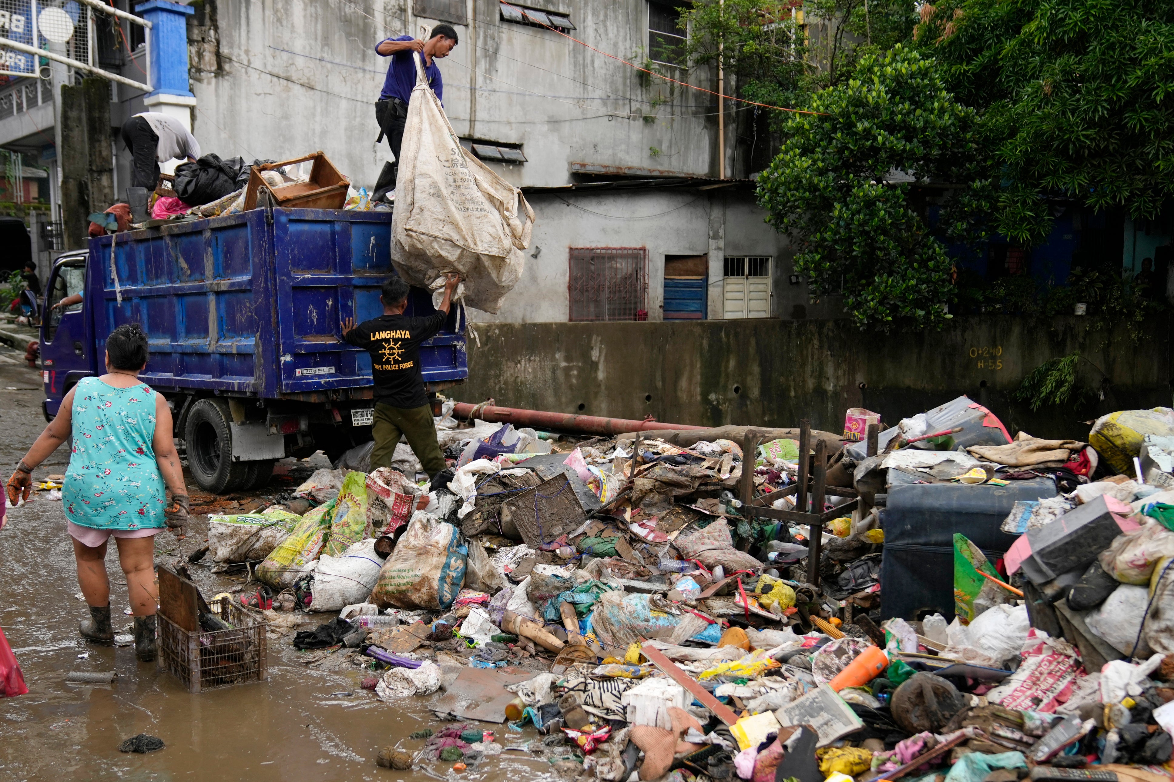 Workers collect trash after flooding caused by Tropical Storm Yagi (known locally as Enteng) subsided in Antipolo City, Rizal Province, Philippines