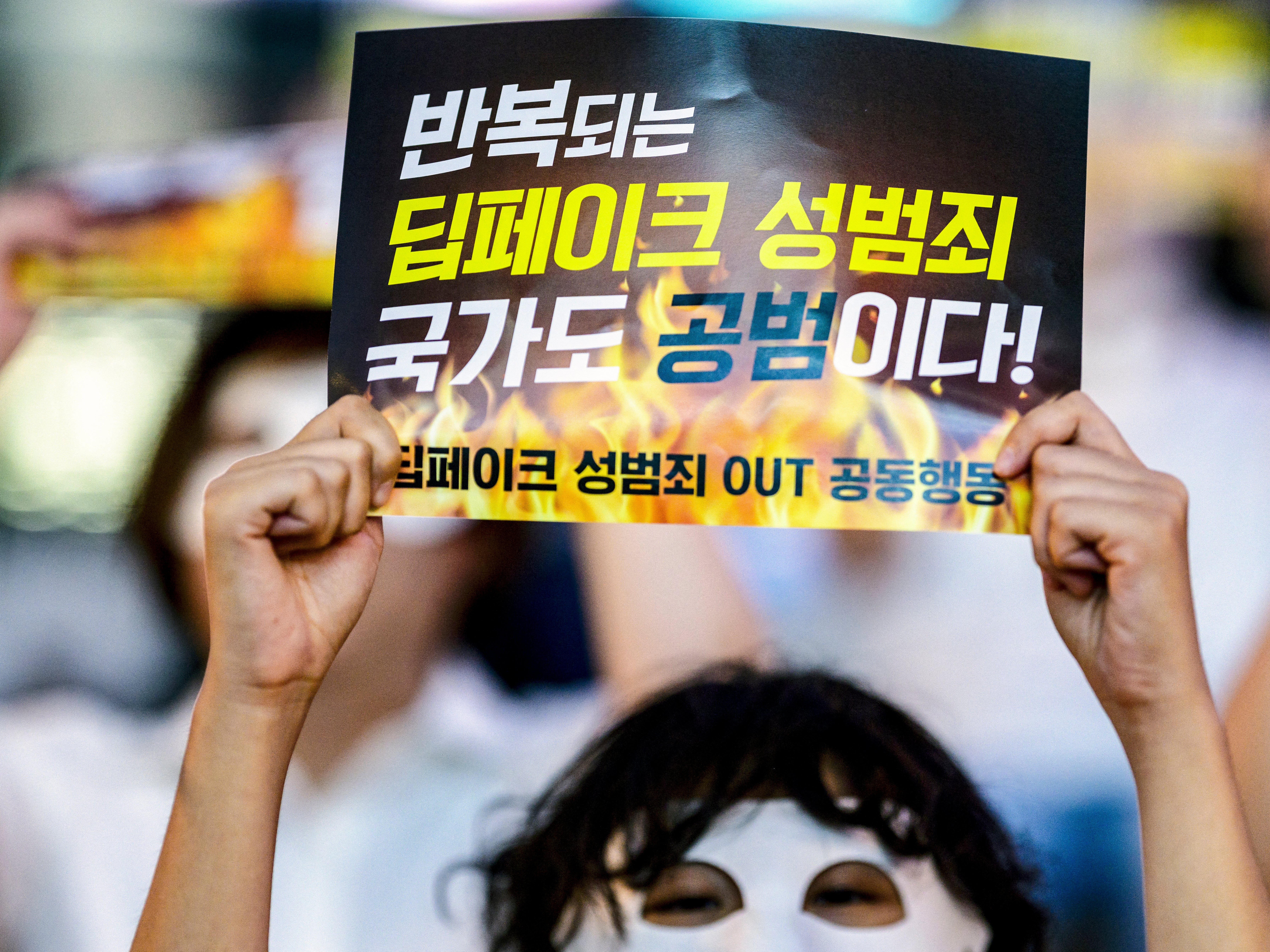 An activist wearing an eye mask, holds a poster reading ‘Repeated deepfake sex crimes, the state is an accomplice too’ during a protest against deepfake porn in Seoul on 30 August 2024