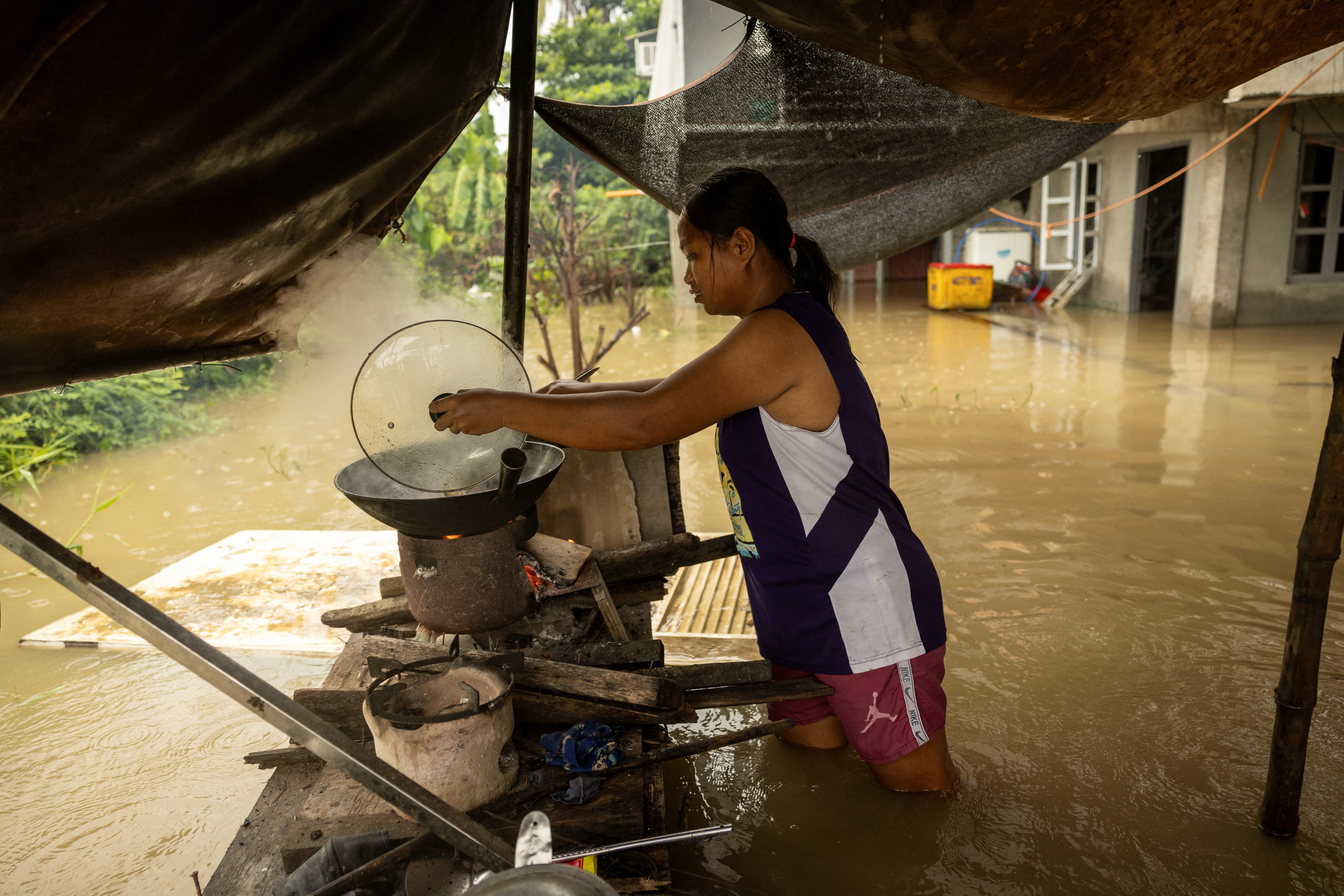 Rosien Bantog, 33, cooks stew amid floodwaters caused by Tropical Storm Yagi (known locally as Enteng) in Apalit, Pampanga province, Philippines.