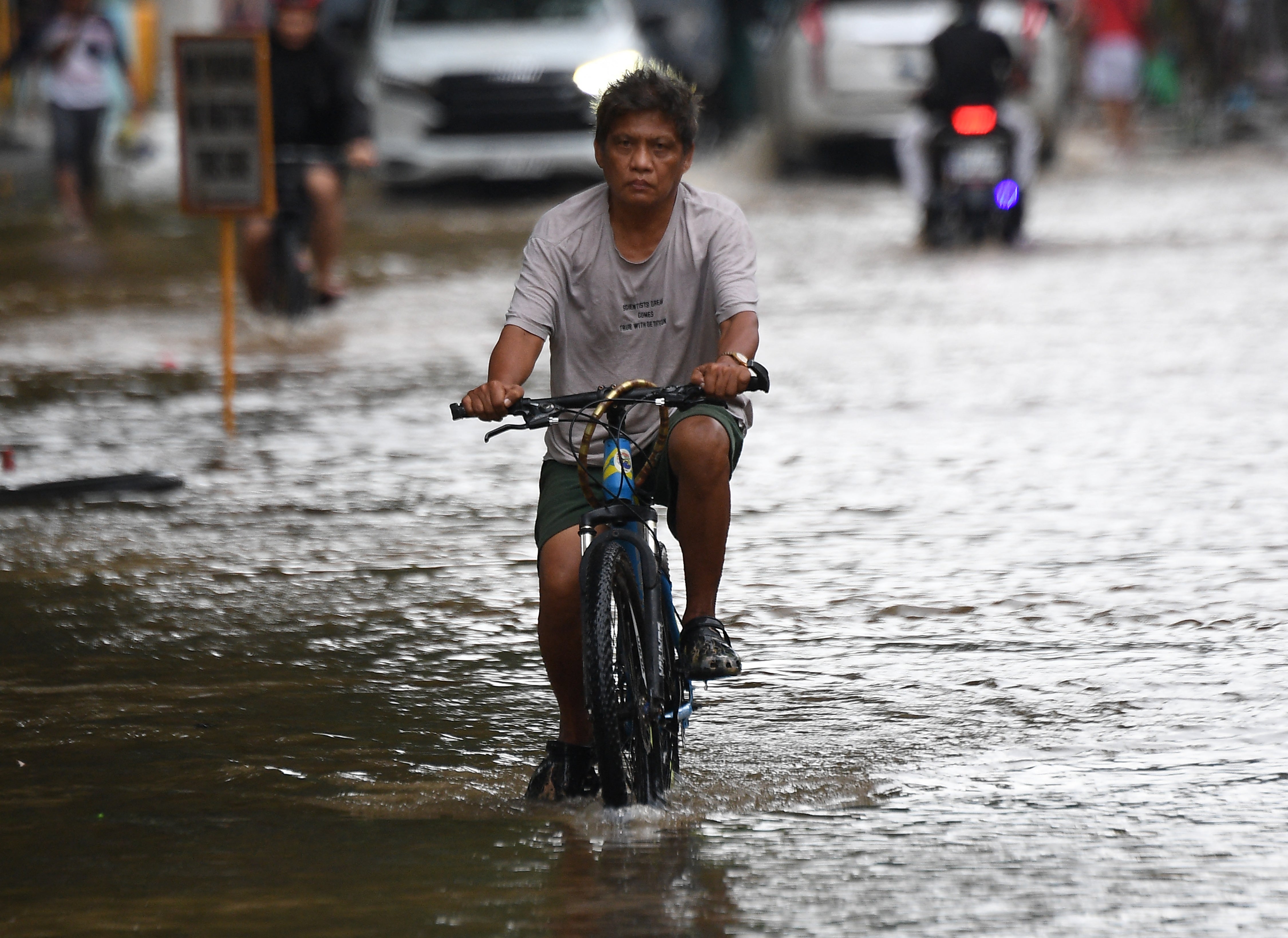 Residents ride their bicycles through a flooded street caused by heavy rains from Tropical Storm Yagi in a village in Cainta town, Rizal province, east of Manila.