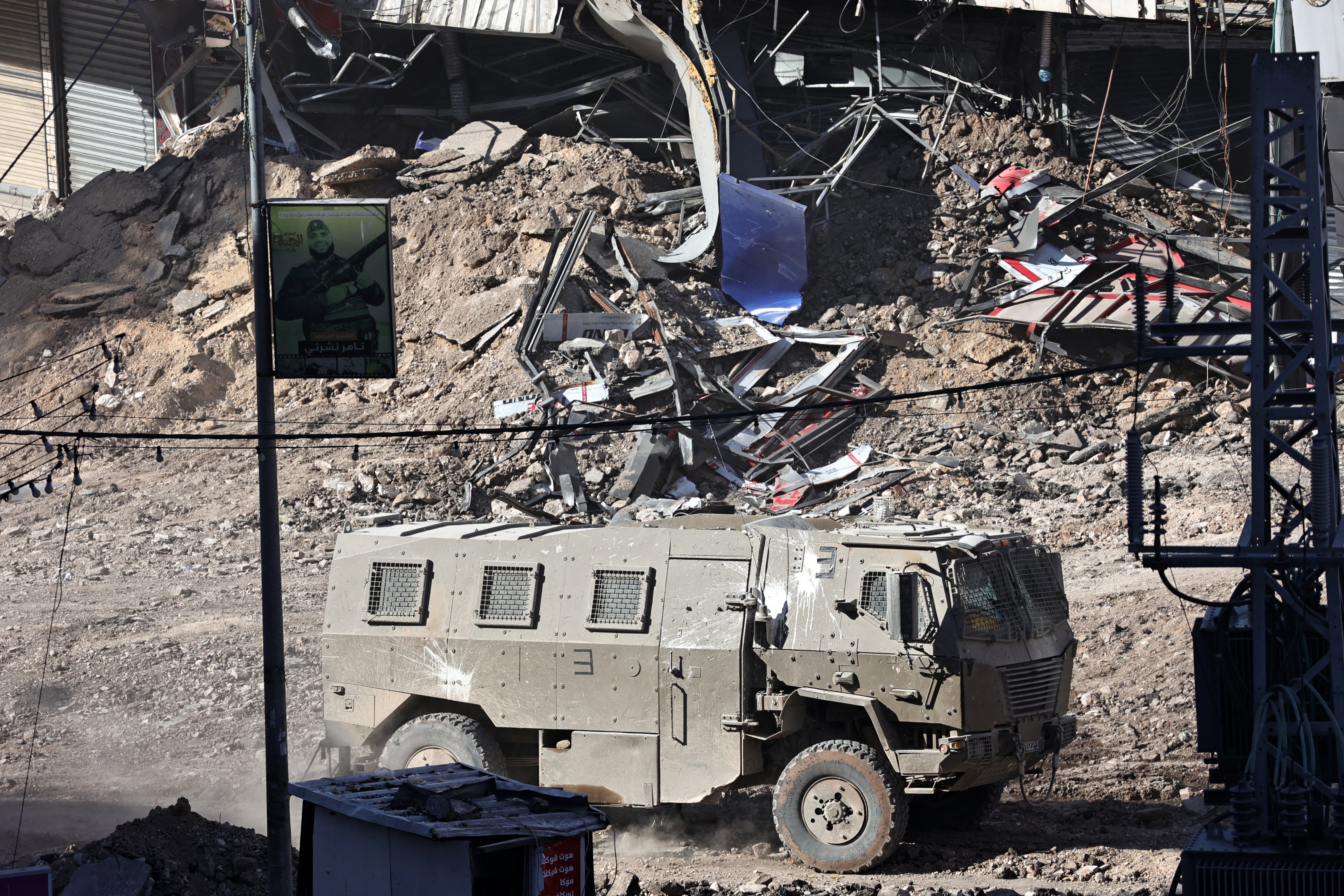 An armed Israeli vehicle drives down a devastated street in Jenin