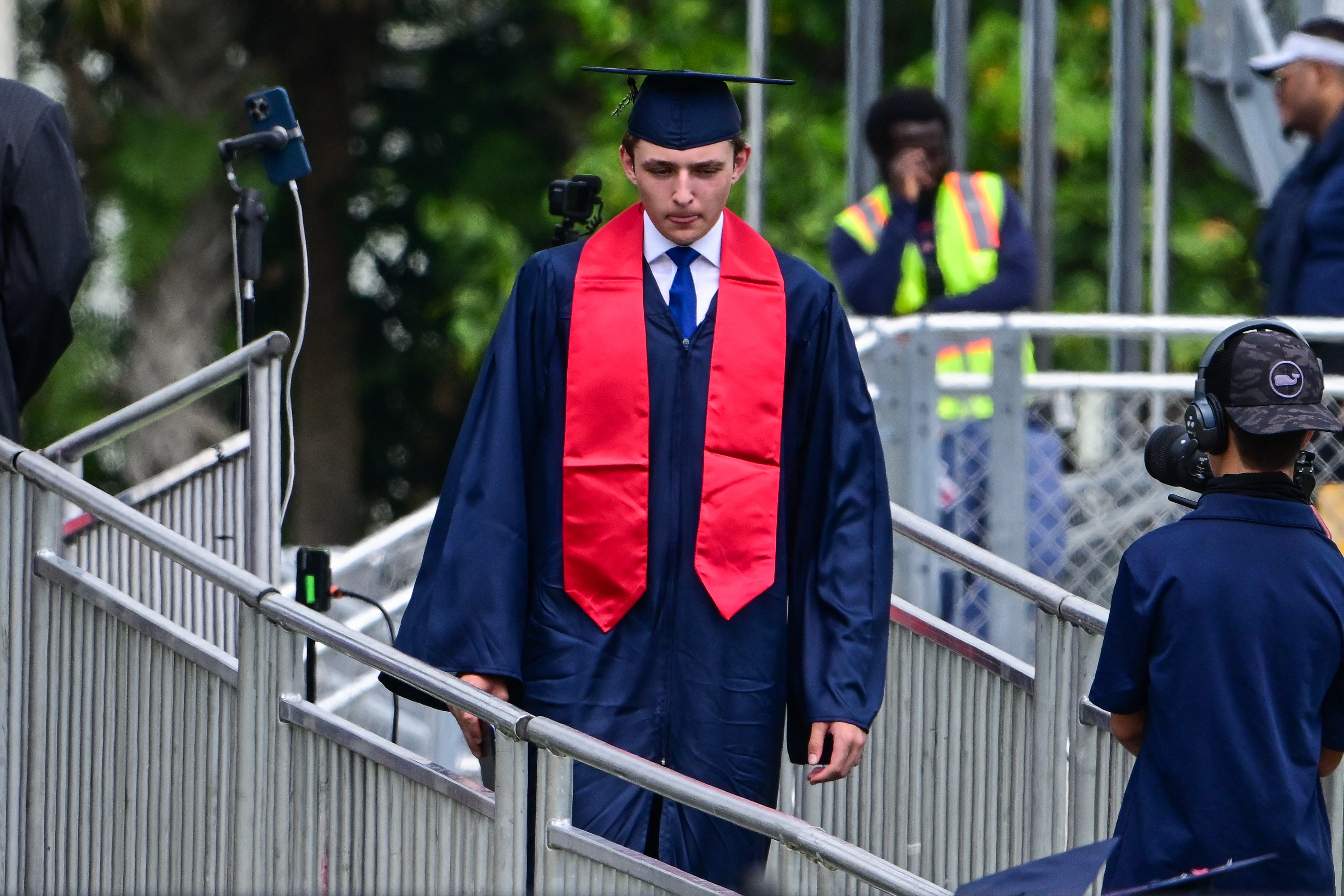 Barron Trump walks off stage at his high school graduation earlier this year. The 18-year-old now attends New York University, where many students are taking rushed and blurry videos of him as he goes about his day