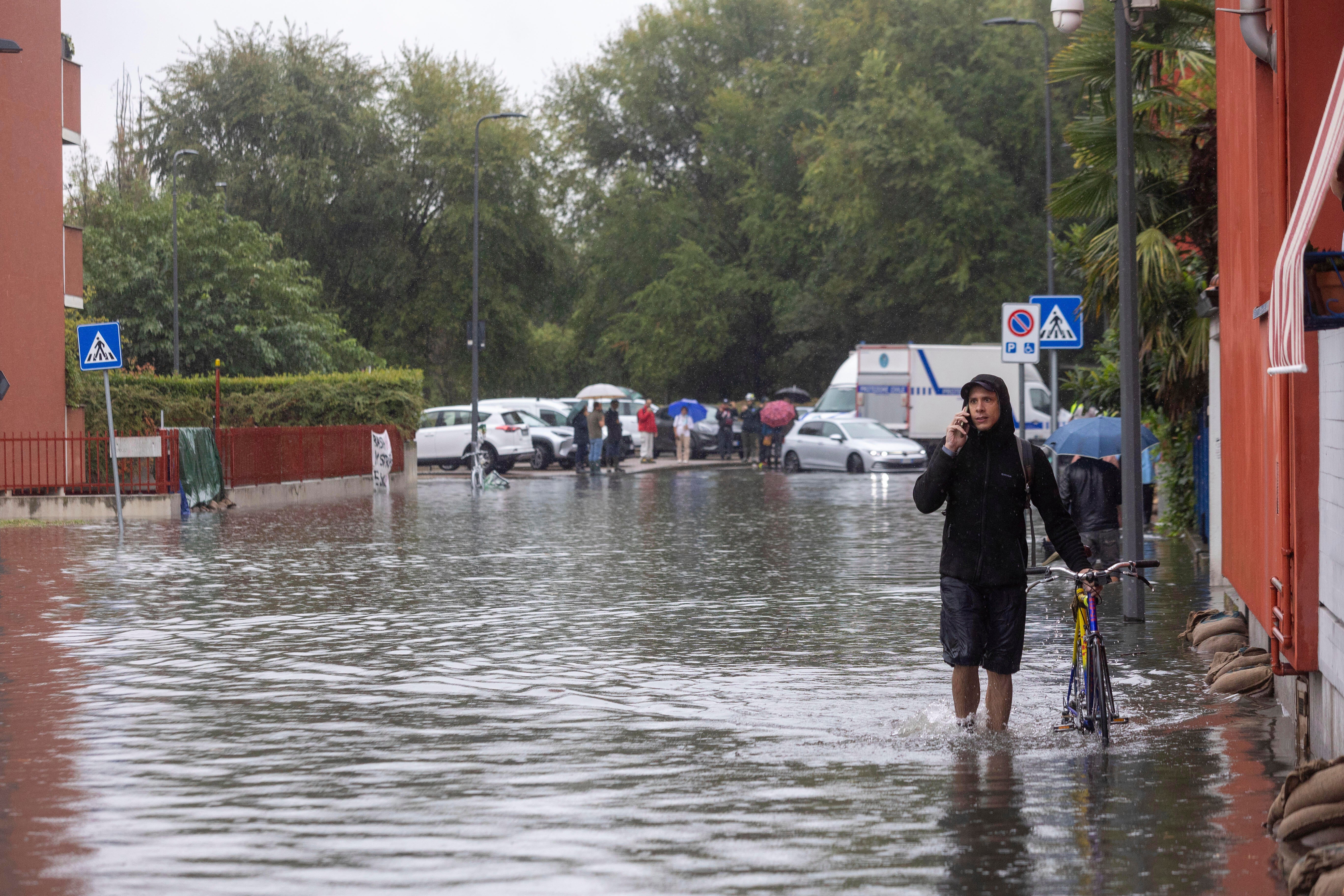 Residents walk through flooded streets in Milan, northern Italy, Thursday