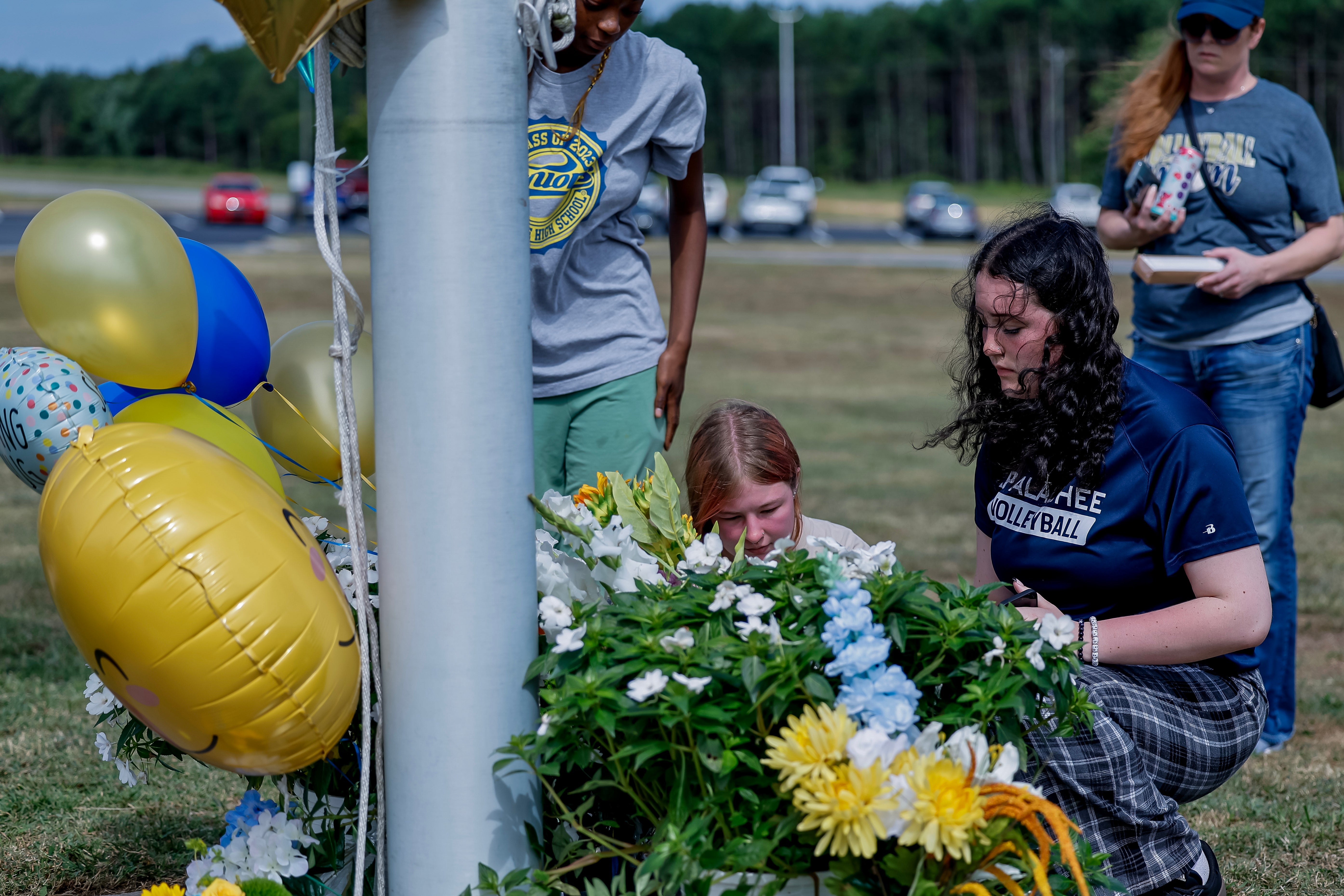 Mourners kneel outside a vigil for the two students and two teachers killed by a gunman at Apalachee High School on Wednesday