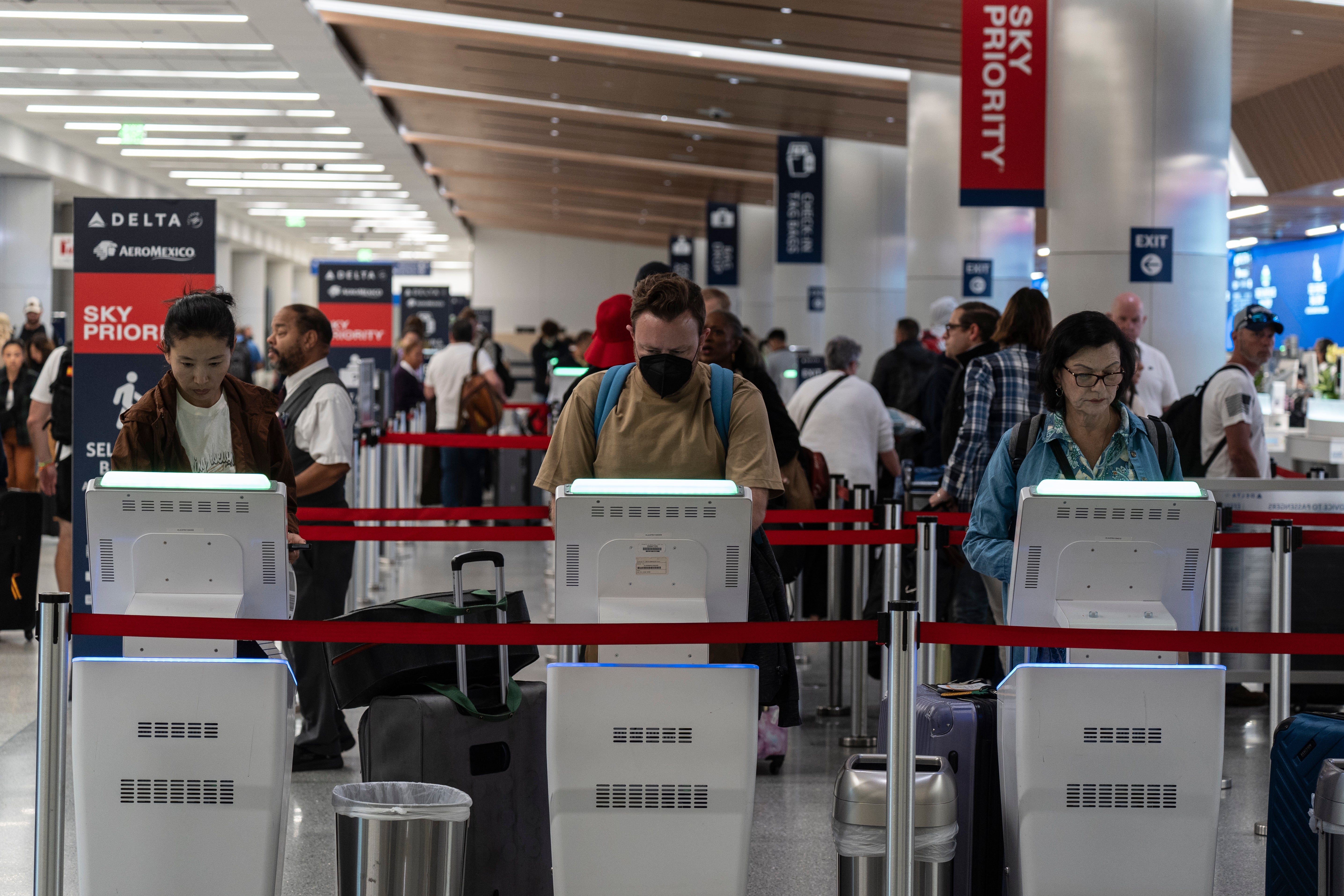 Os viajantes usam quiosques para fazer check-in de voos na área de bilheteria da Delta Airlines no Aeroporto Internacional de Los Angeles, em Los Angeles, sexta-feira, 30 de agosto de 2024