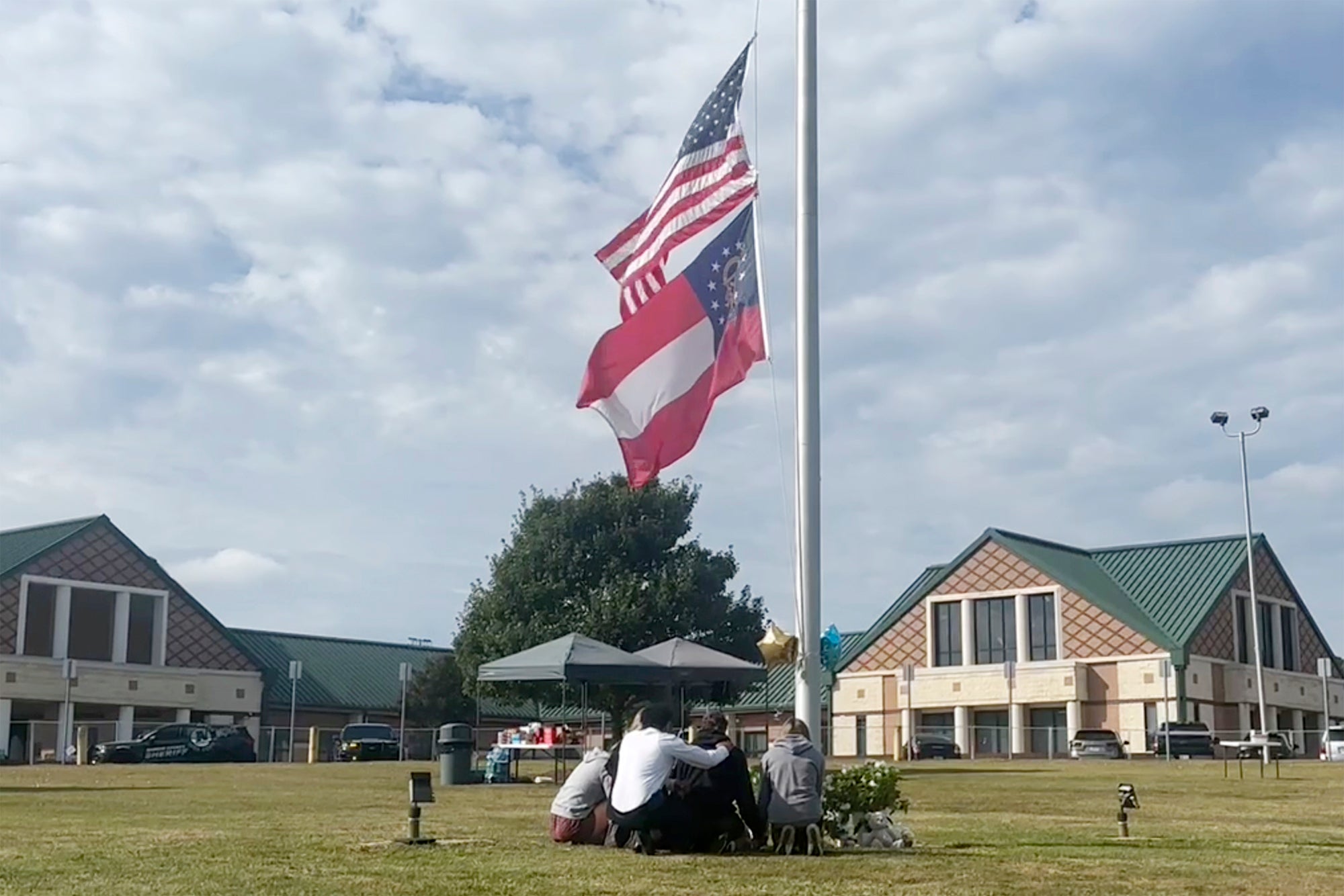 People gather at the flagpole outside the entrance to Apalachee High School on Thursday, Sept. 5, 2024 in Winder, Ga., a day after deadly shootings at the school.