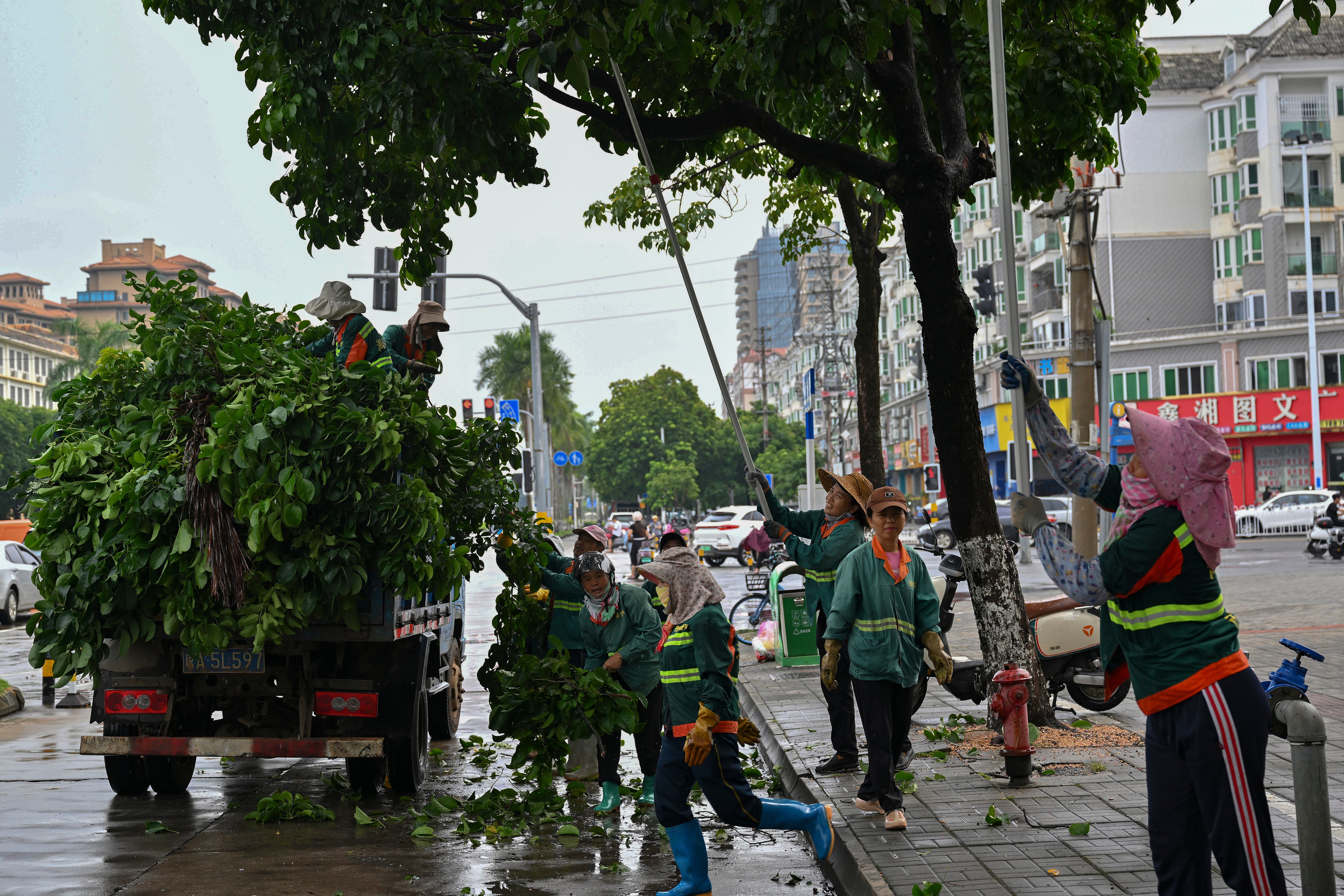 Workers cut redundant branches off of trees along a street ahead of the landfall of typhoon Yagi in Haikou, south China’s Hainan Province