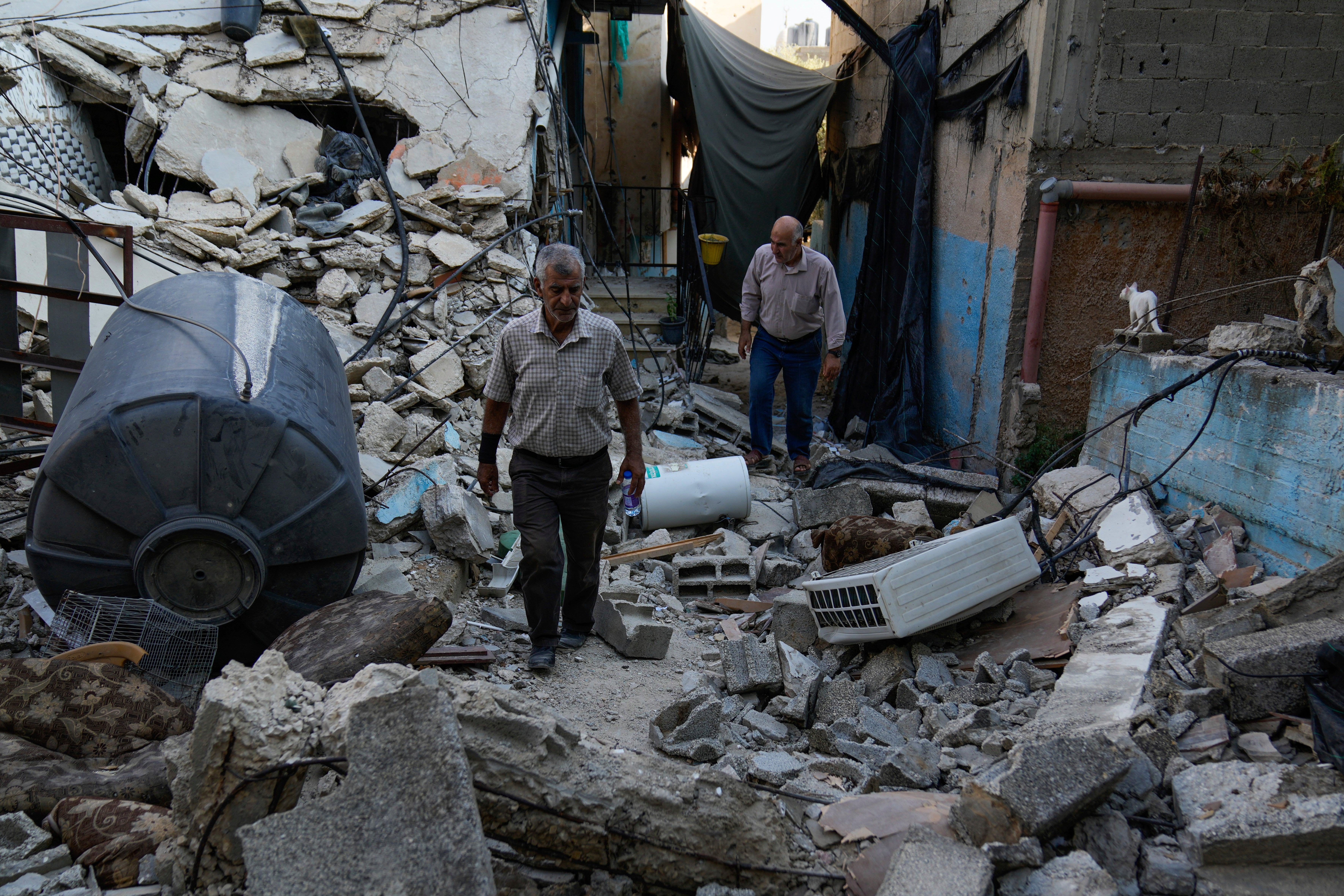 Palestinians survey the damage after Israeli forces raided the West Bank city of Jenin on Friday