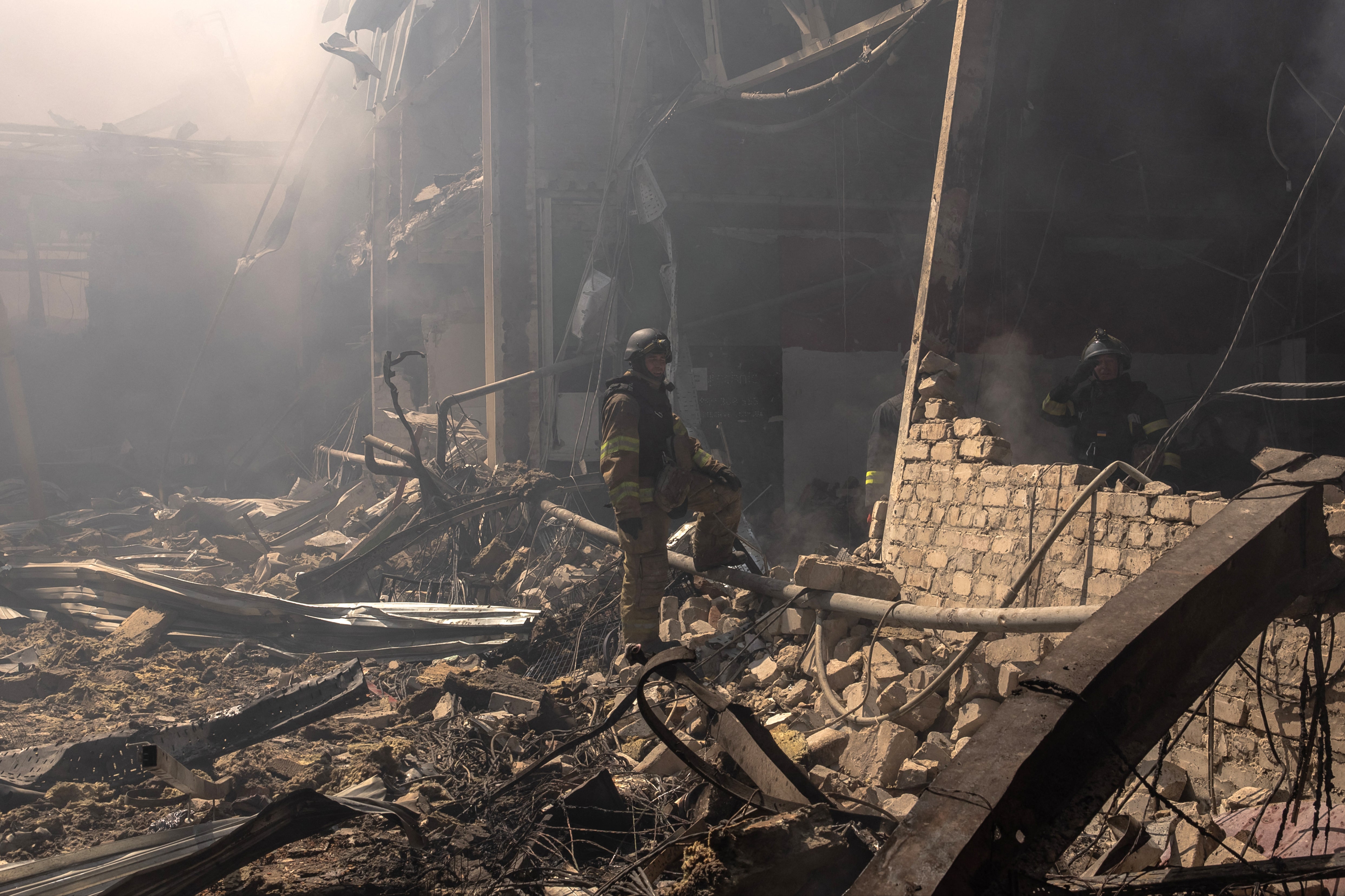 Ukrainian emergency and rescue workers stand in the debris at a destroyed supermarket in August